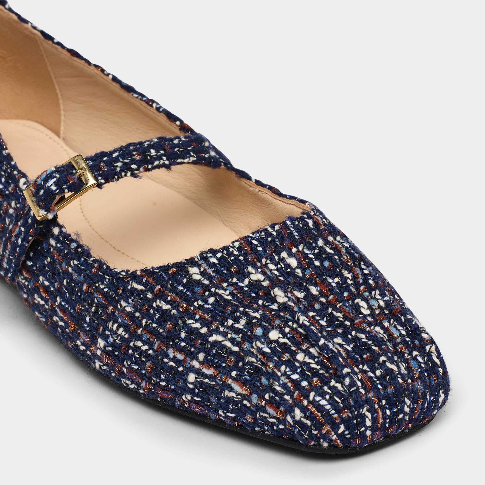 Flats with a textured pattern and gold buckle on a light gray background