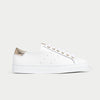 White sneaker with gold accents on a light gray background