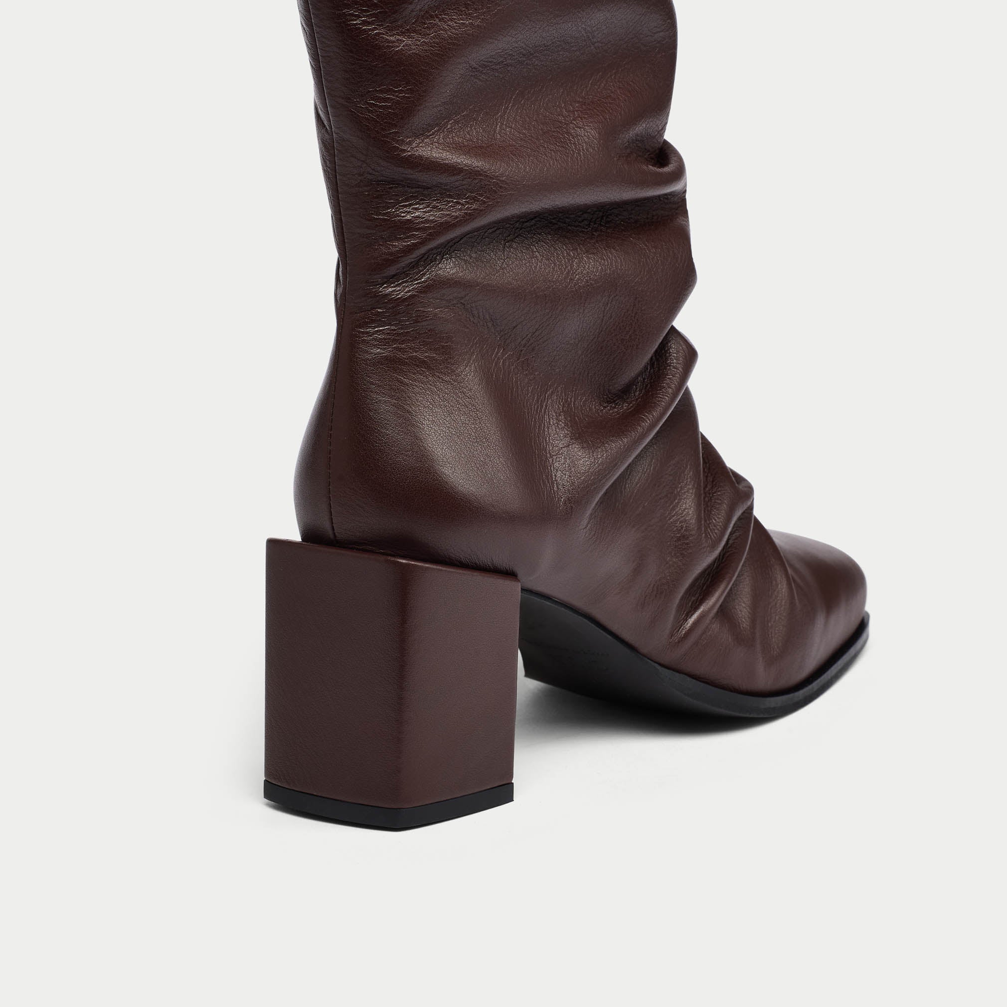 Brown knee-high boot with a block heel on a light gray background