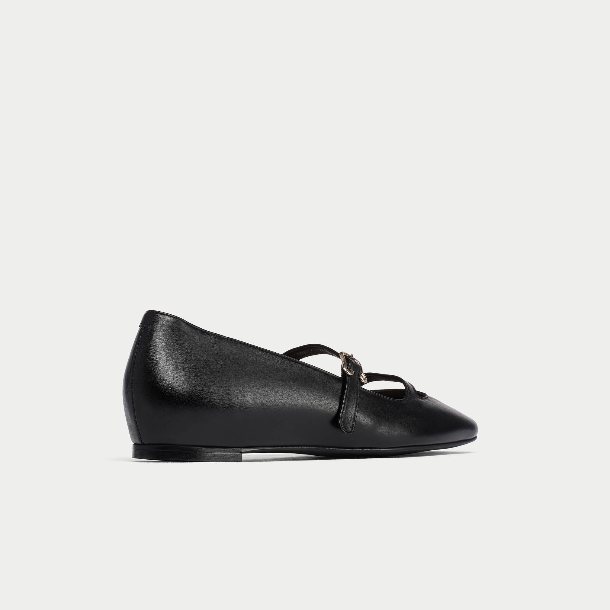 Black leather flat shoe with a bow on a light gray background