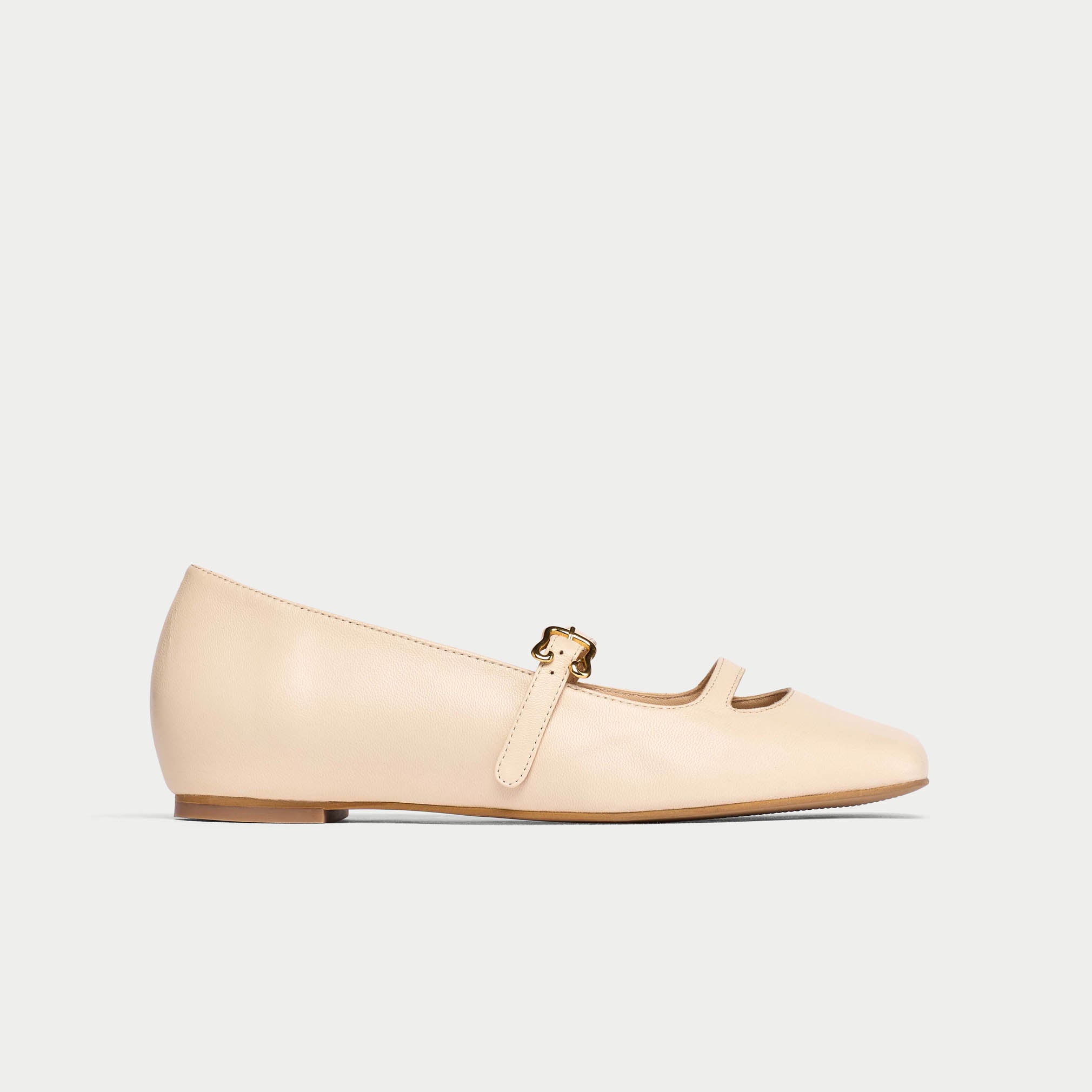Beige flat shoe with a strap on a light gray background
