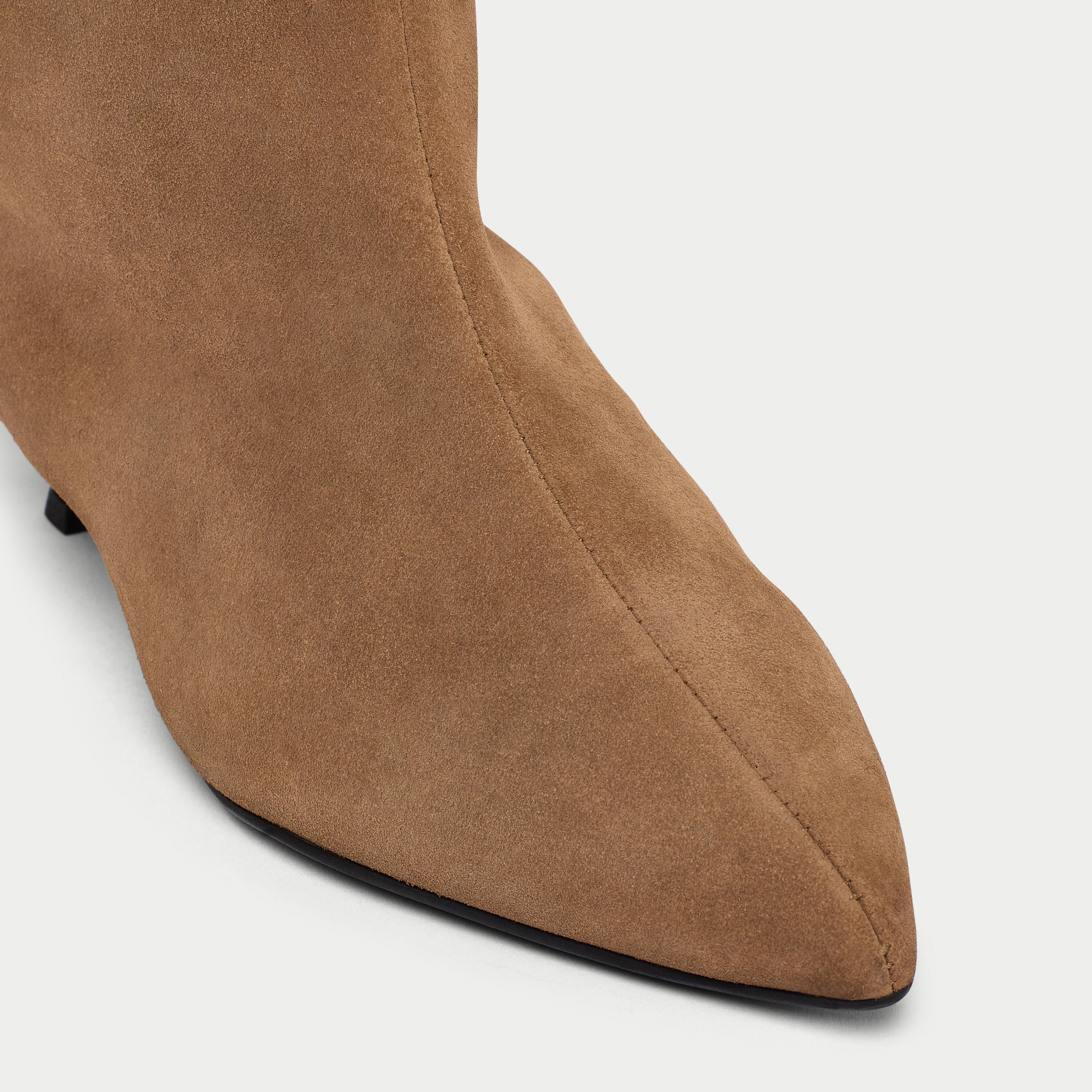 Close-up of a brown suede boot on a light gray background