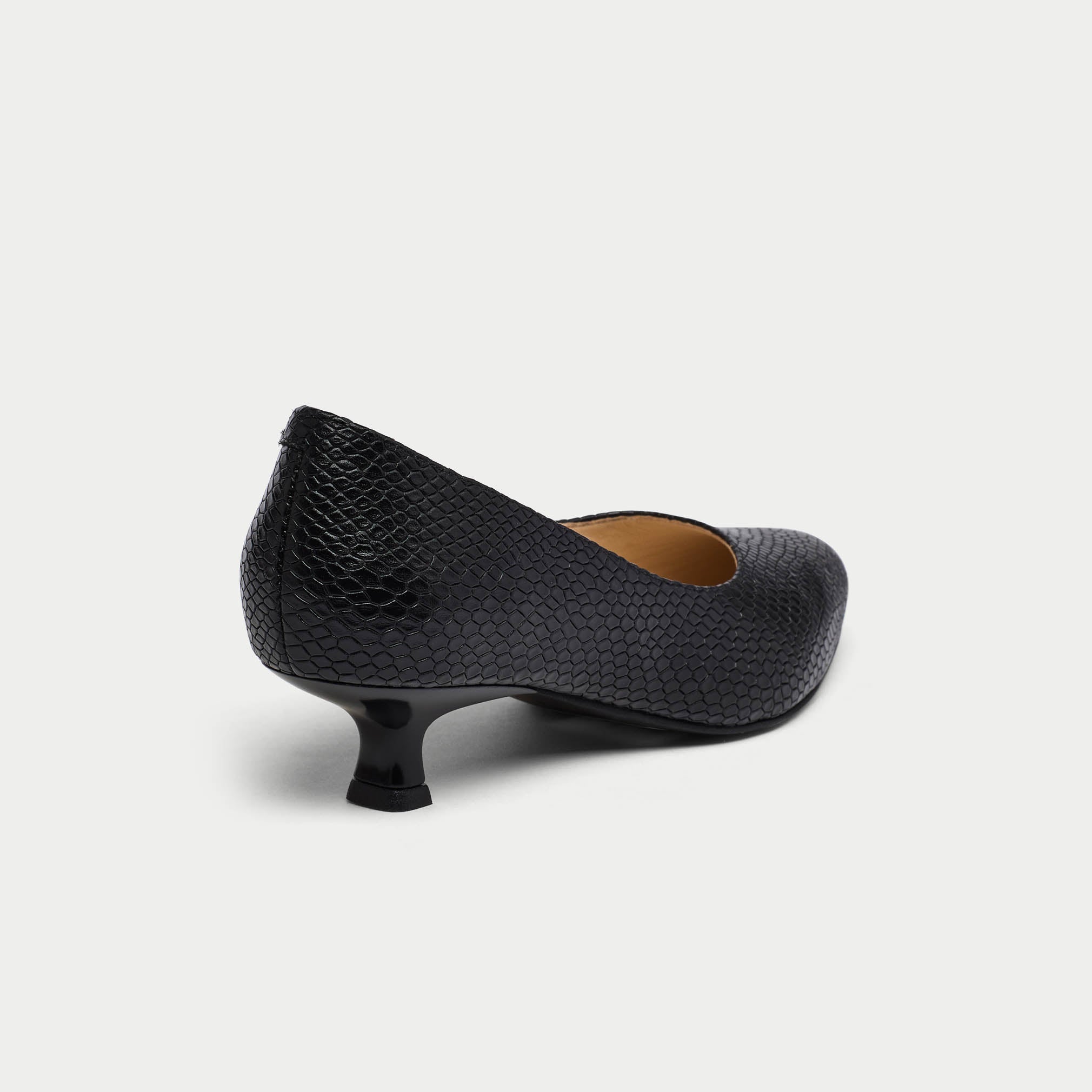 Black textured high heel shoe on a light gray background