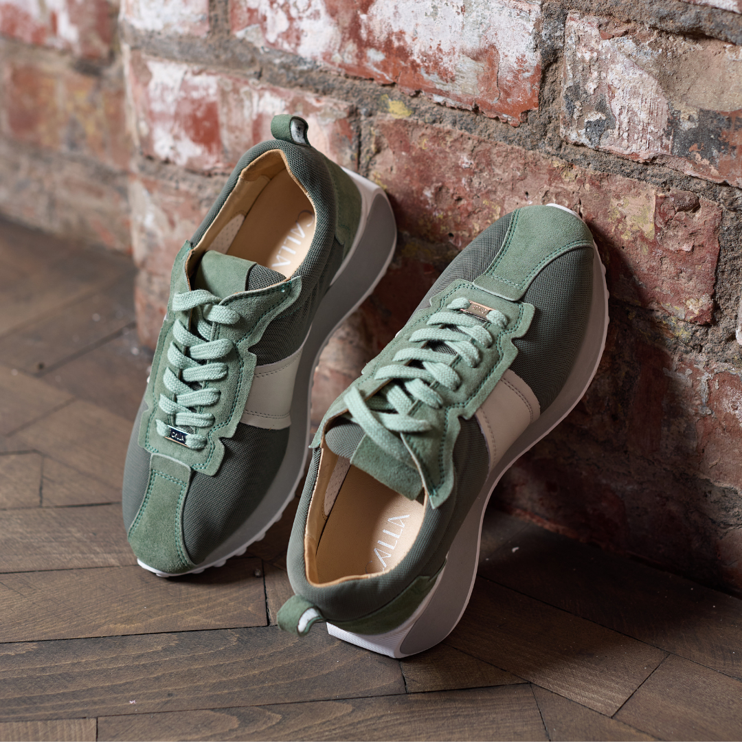 Pair of cosmos mist sneakers on a wooden floor with a brick wall background