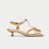 Gold sandal with a thin strap on a light gray background