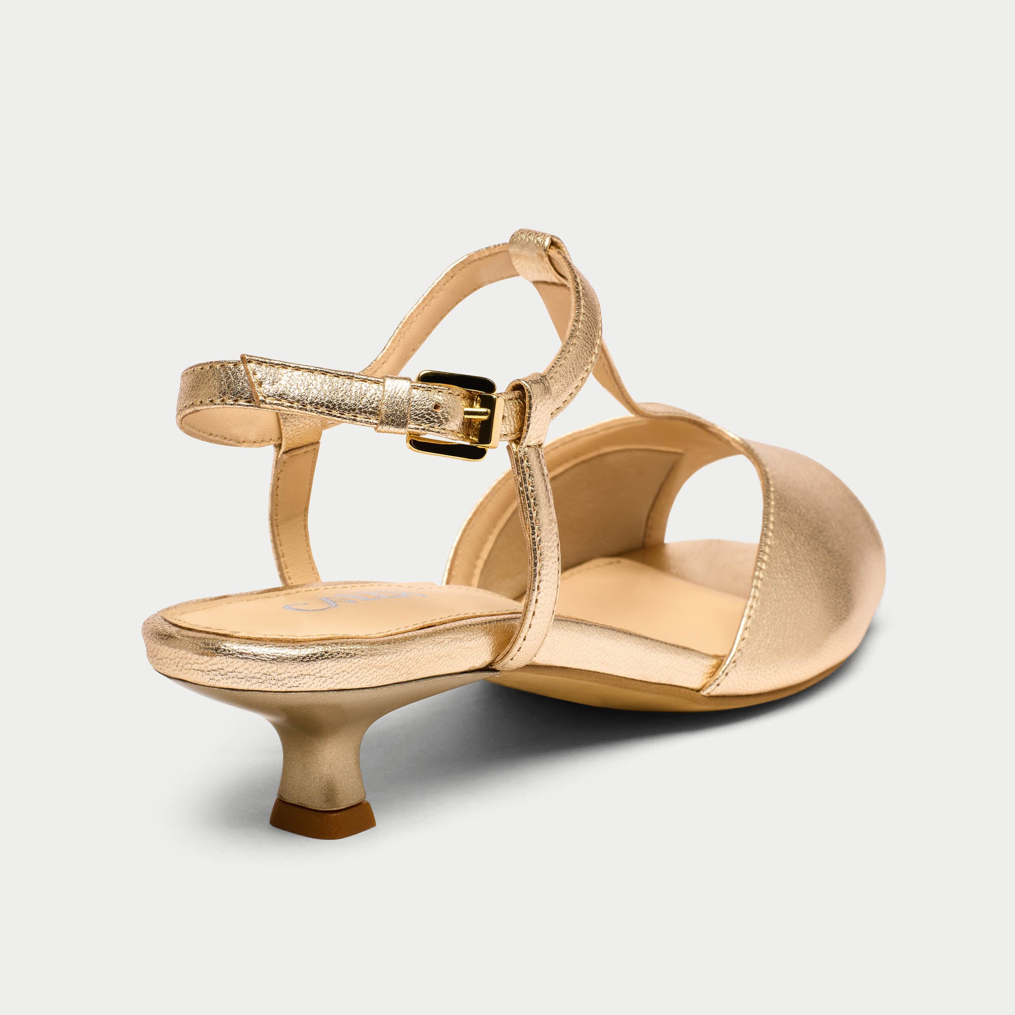 Gold high-heeled shoes on a light gray background