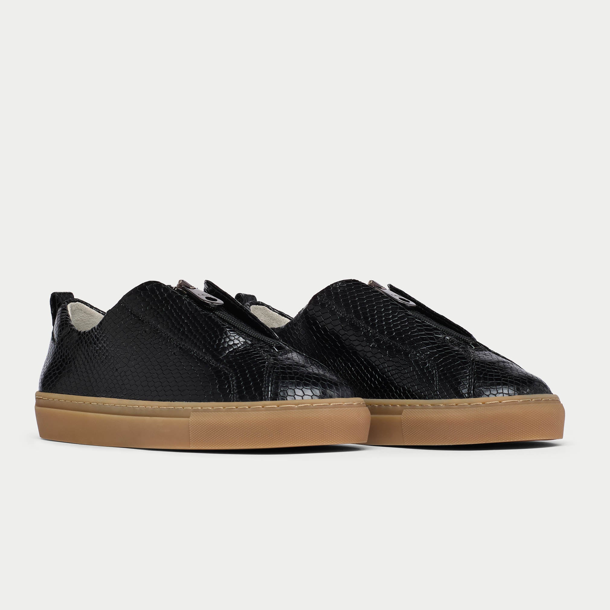 Black Estella sneakers with brown soles on a light gray background