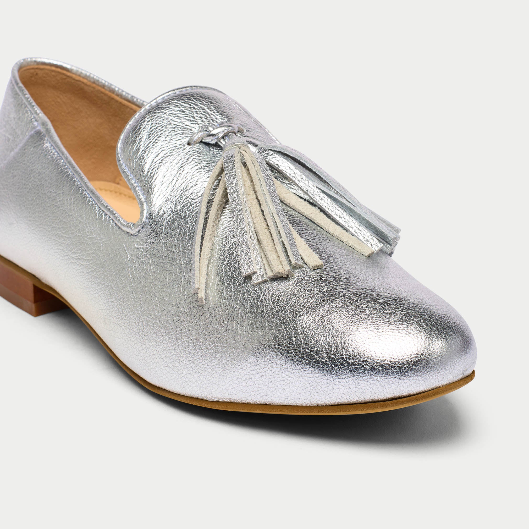 Silver loafer shoe with tassel on a white background