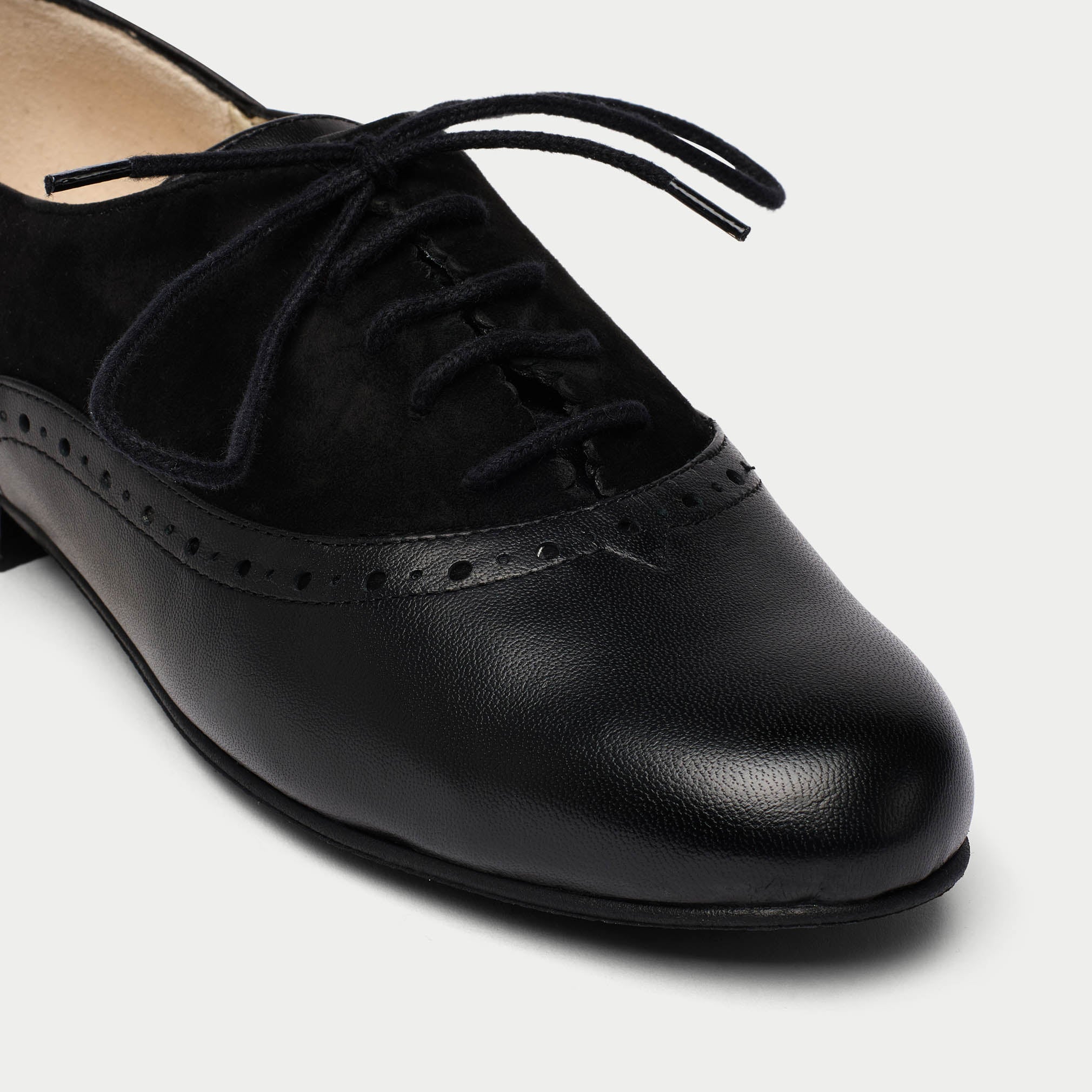 Black leather shoe with laces on a light gray background