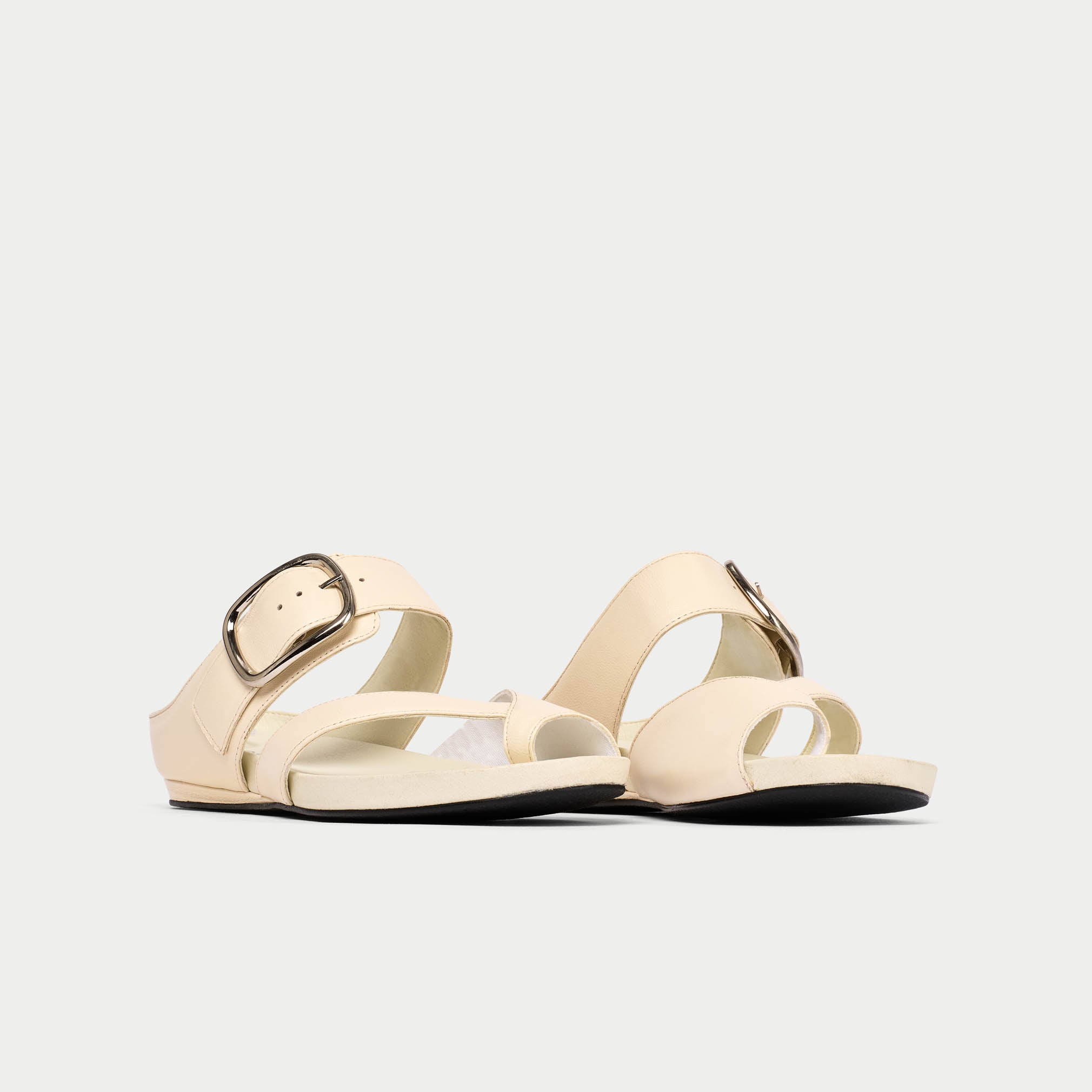 Beige sandal with a decorative buckle on a light gray background