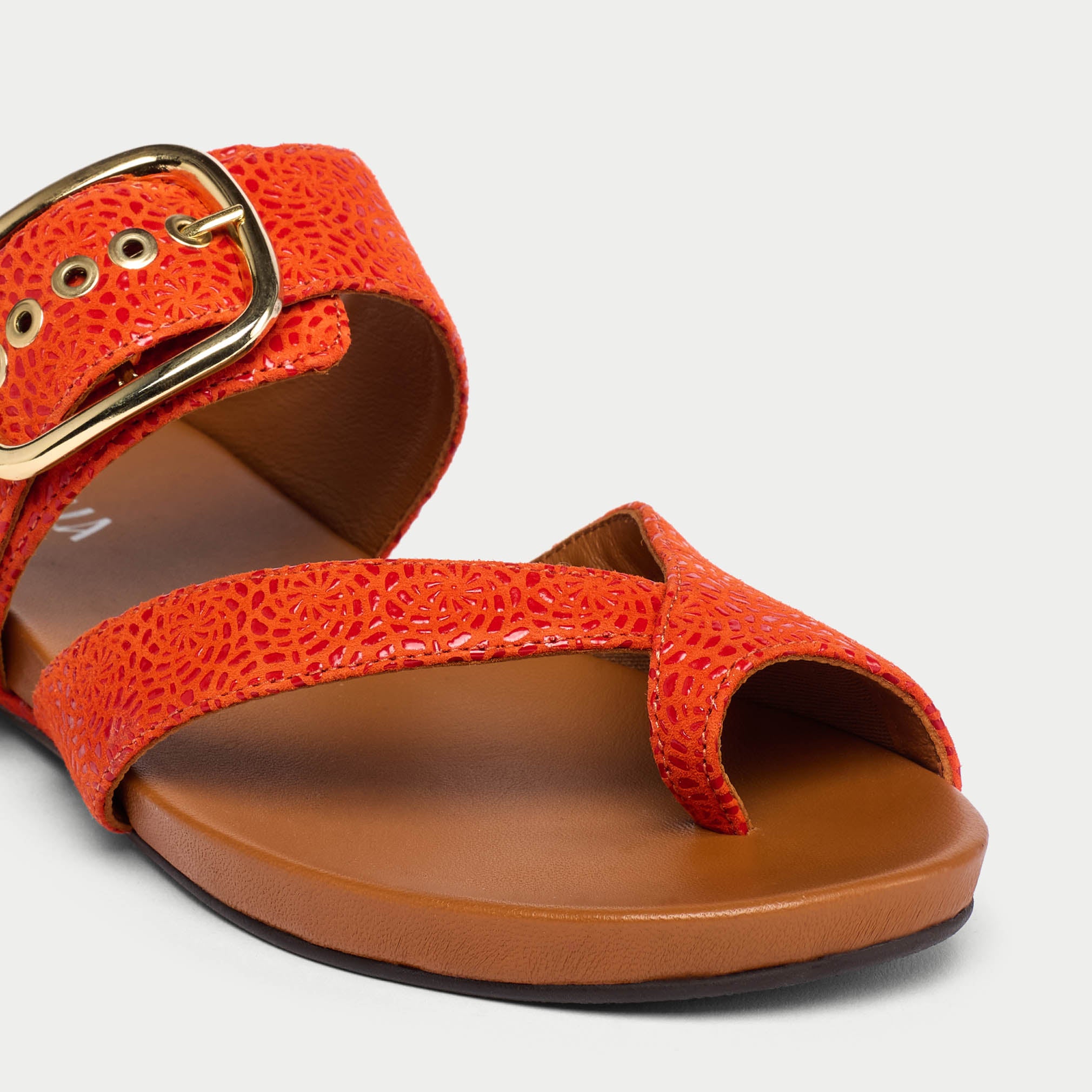 Orange sandal with a gold buckle on a white background