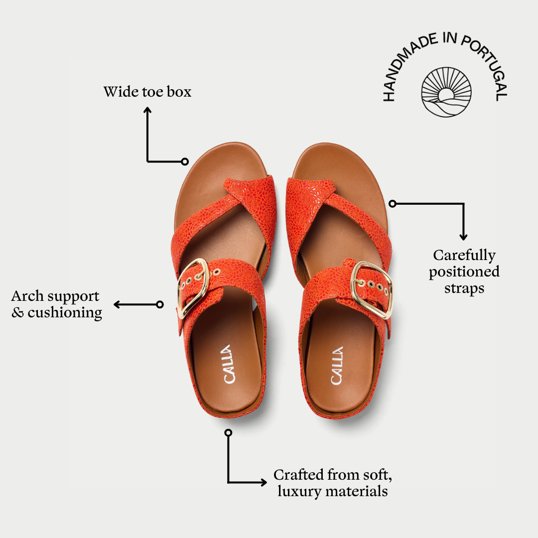 Red sandals with brown soles on a white background, featuring text labels about shoe features.