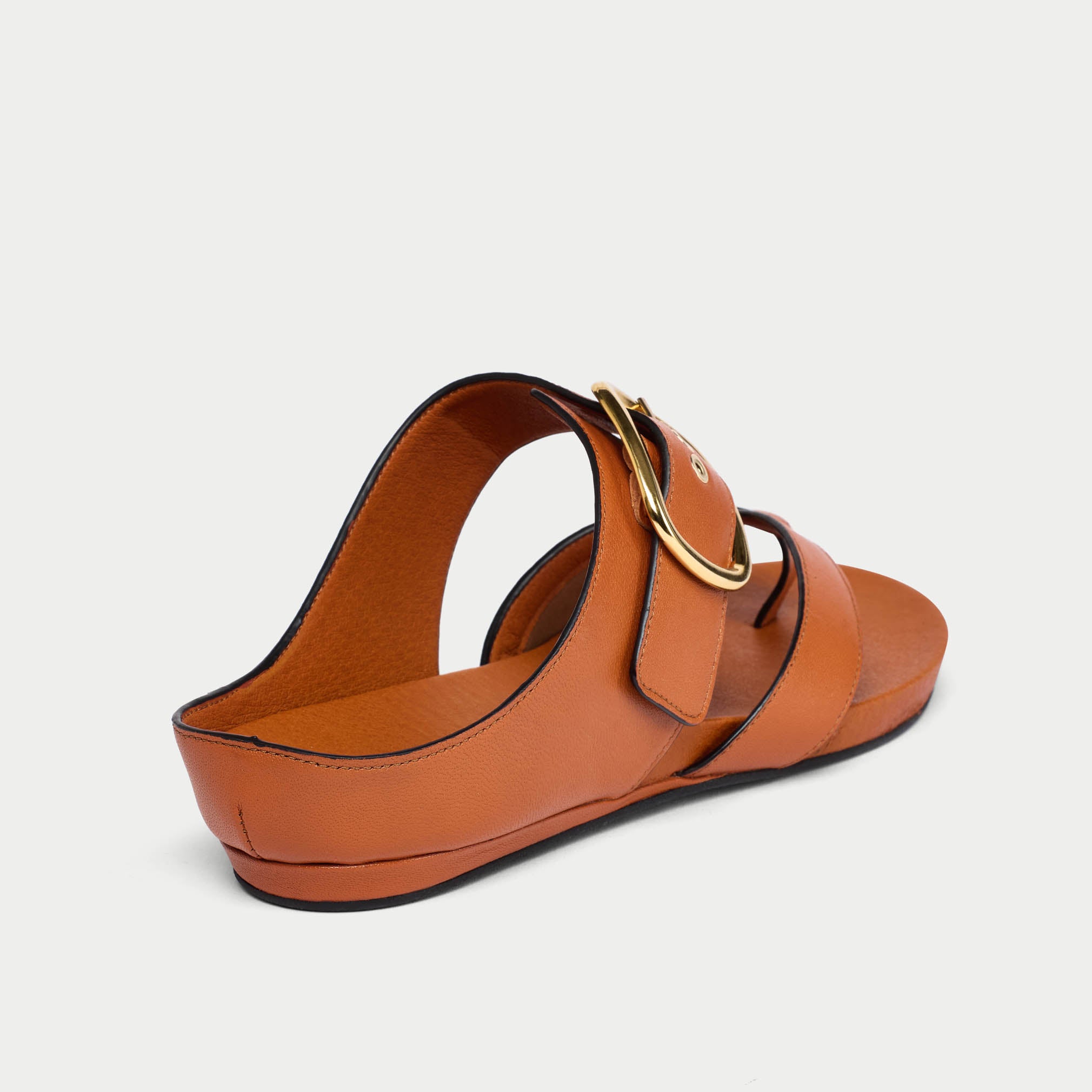 Brown sandal with a gold buckle on a light gray background