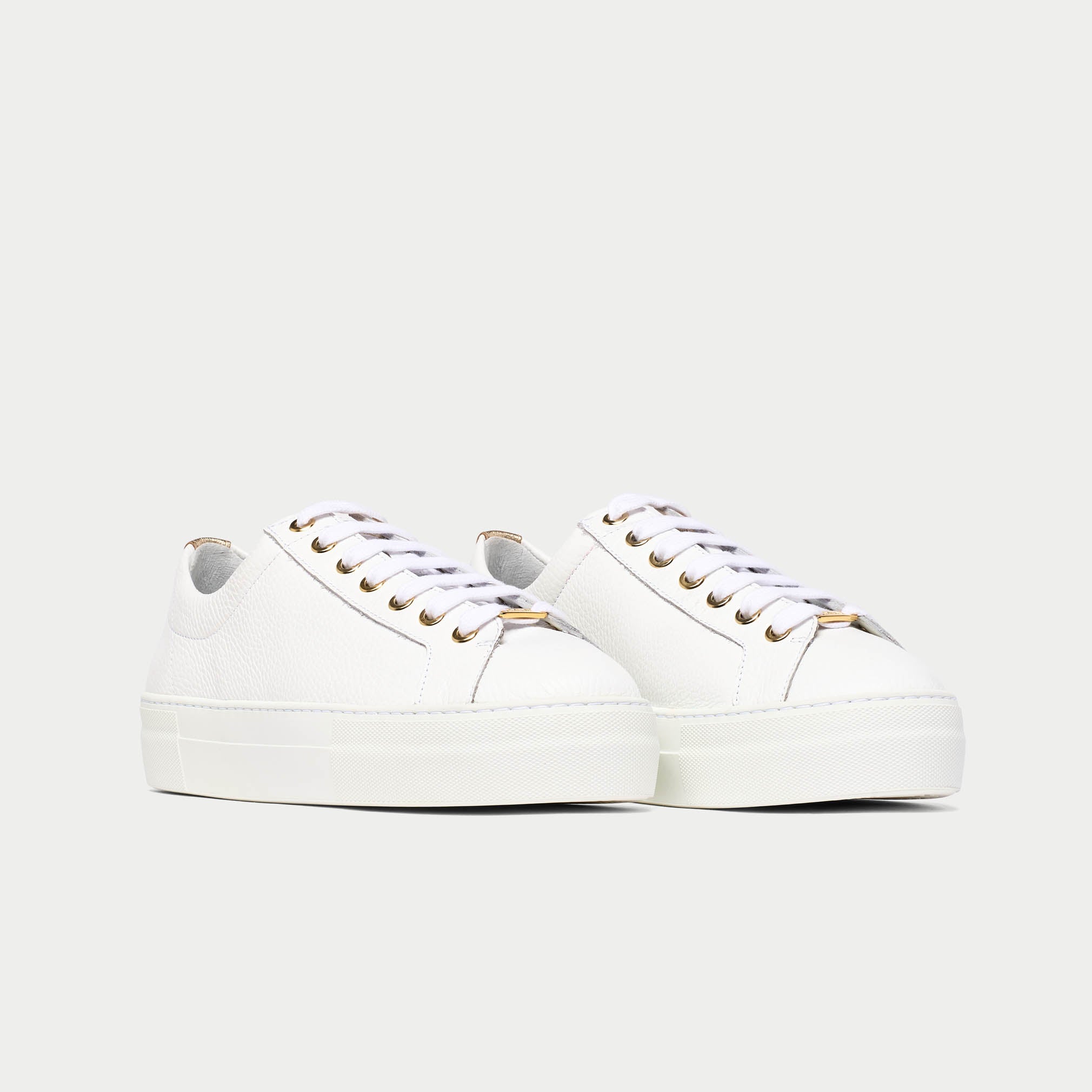 White saturn sneakers with gold accents on a light gray background