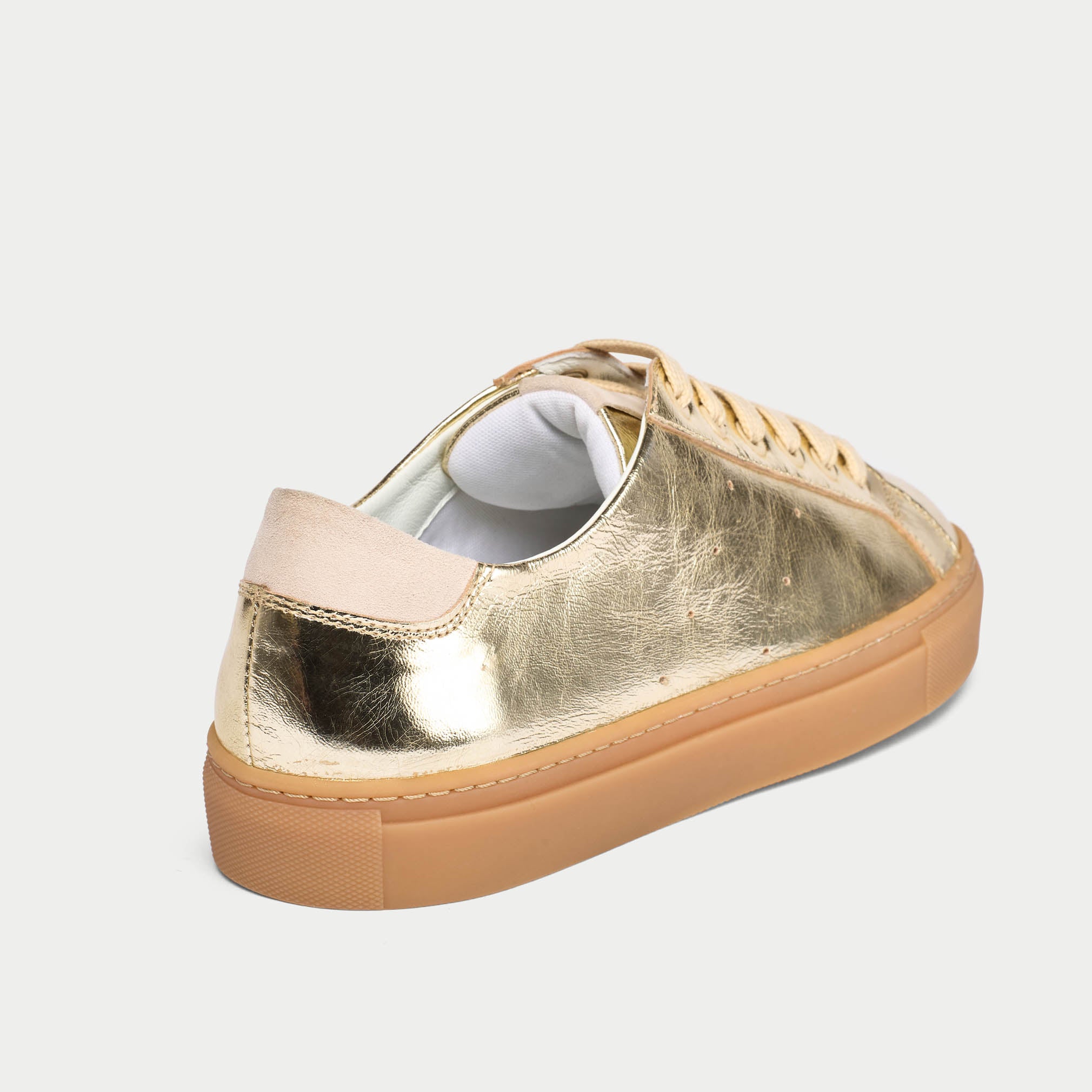 Gold sneaker with beige sole on a light gray background
