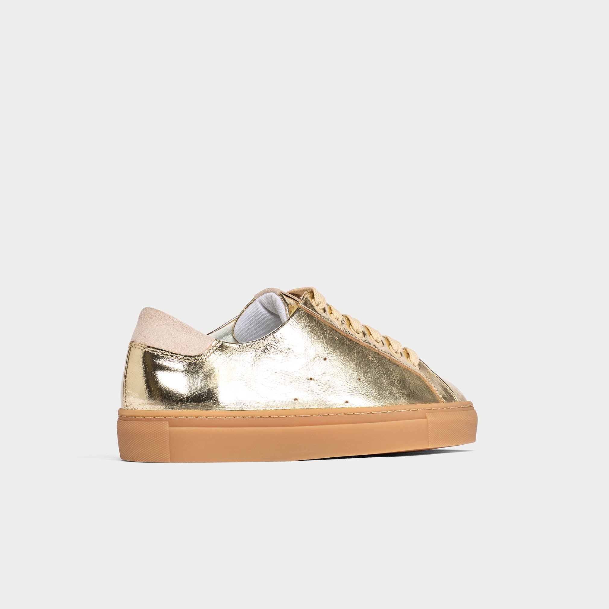 Gold sneaker with beige sole on a light gray background