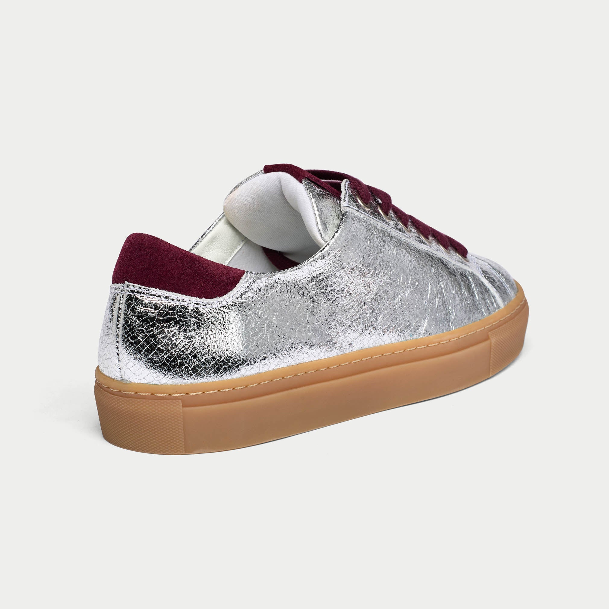 Silver star sneaker with burgundy accents on a light gray background