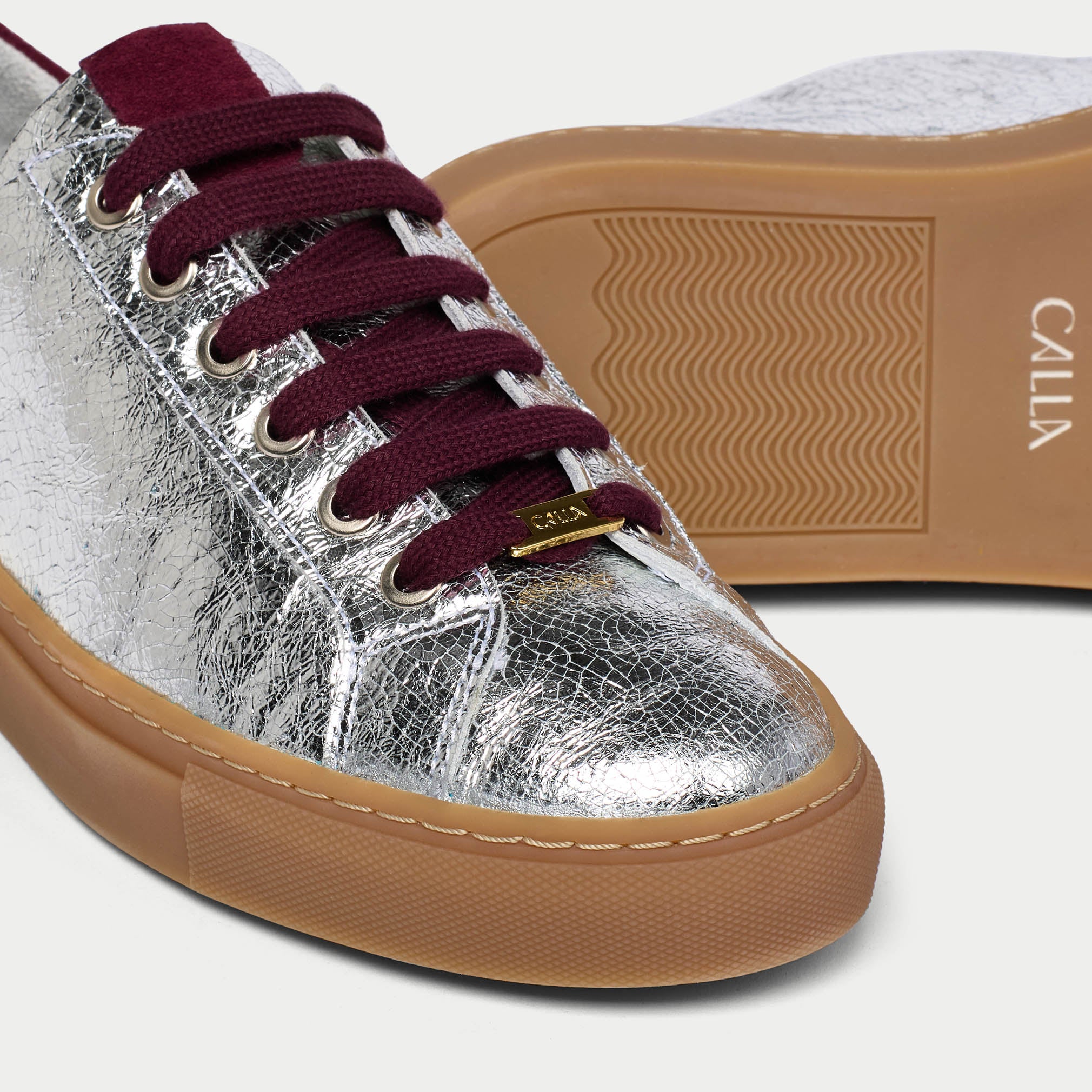 Silver star sneaker with cherry laces and brown sole on a white background