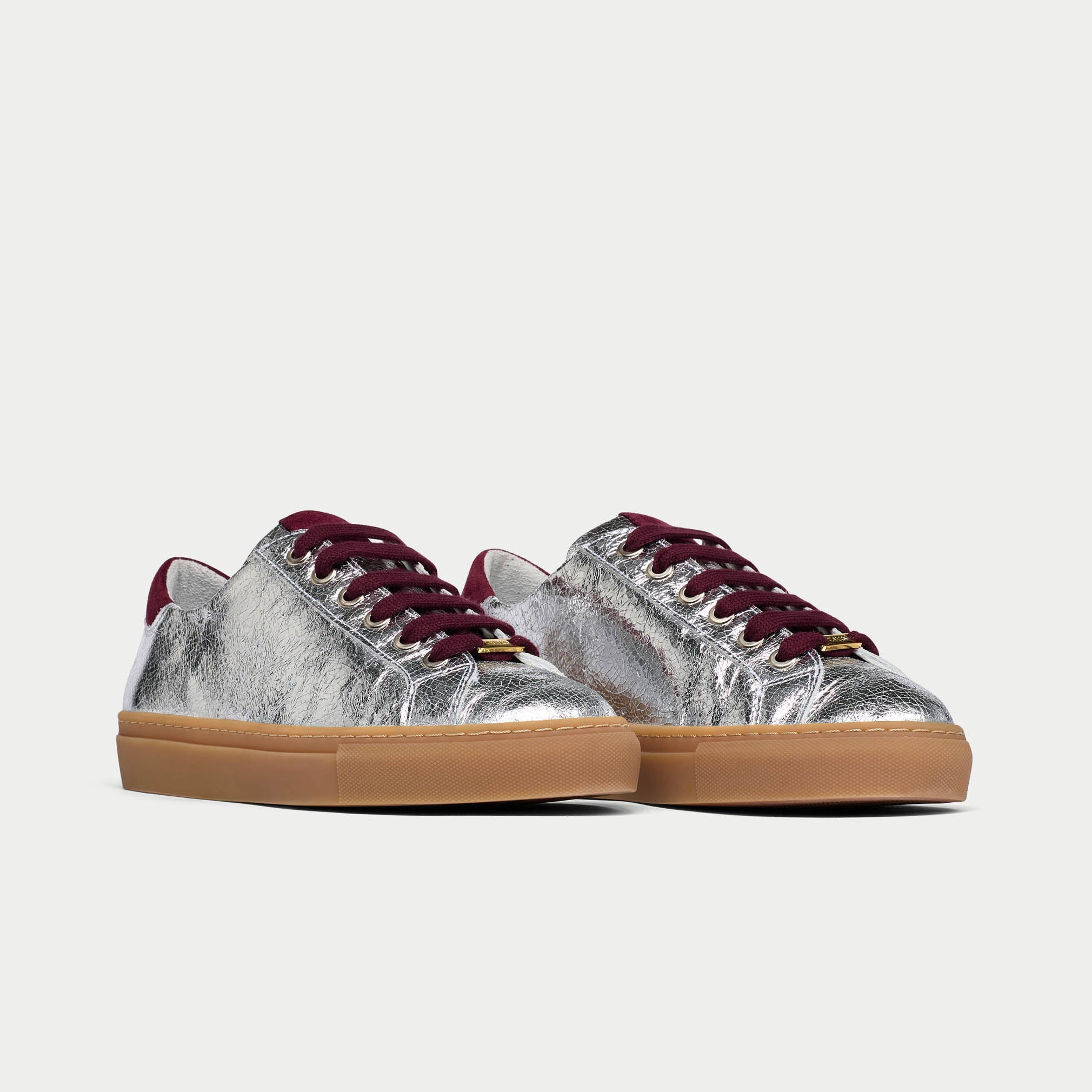 Silver star sneakers with burgundy laces on a light gray background