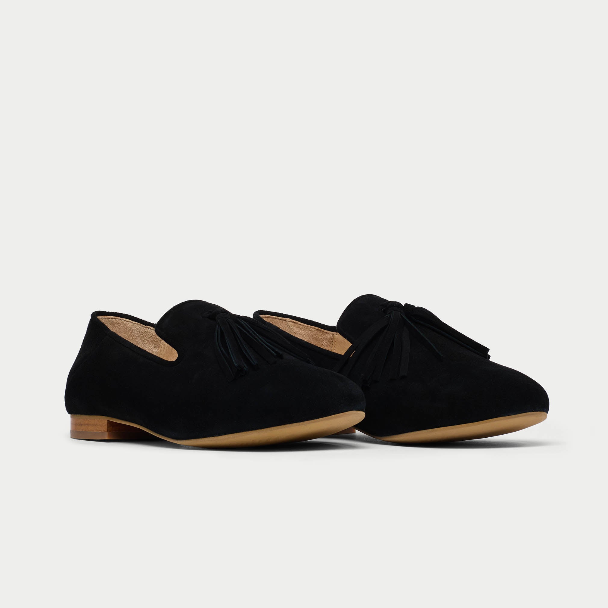 Pair of black loafers with a knot detail on a light gray background