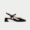 Black patent leather shoe with a strap on a light gray background