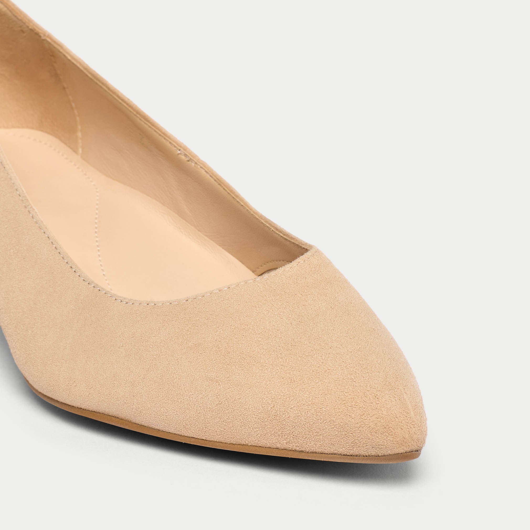 Beige kitten-heeled shoe on a light gray background