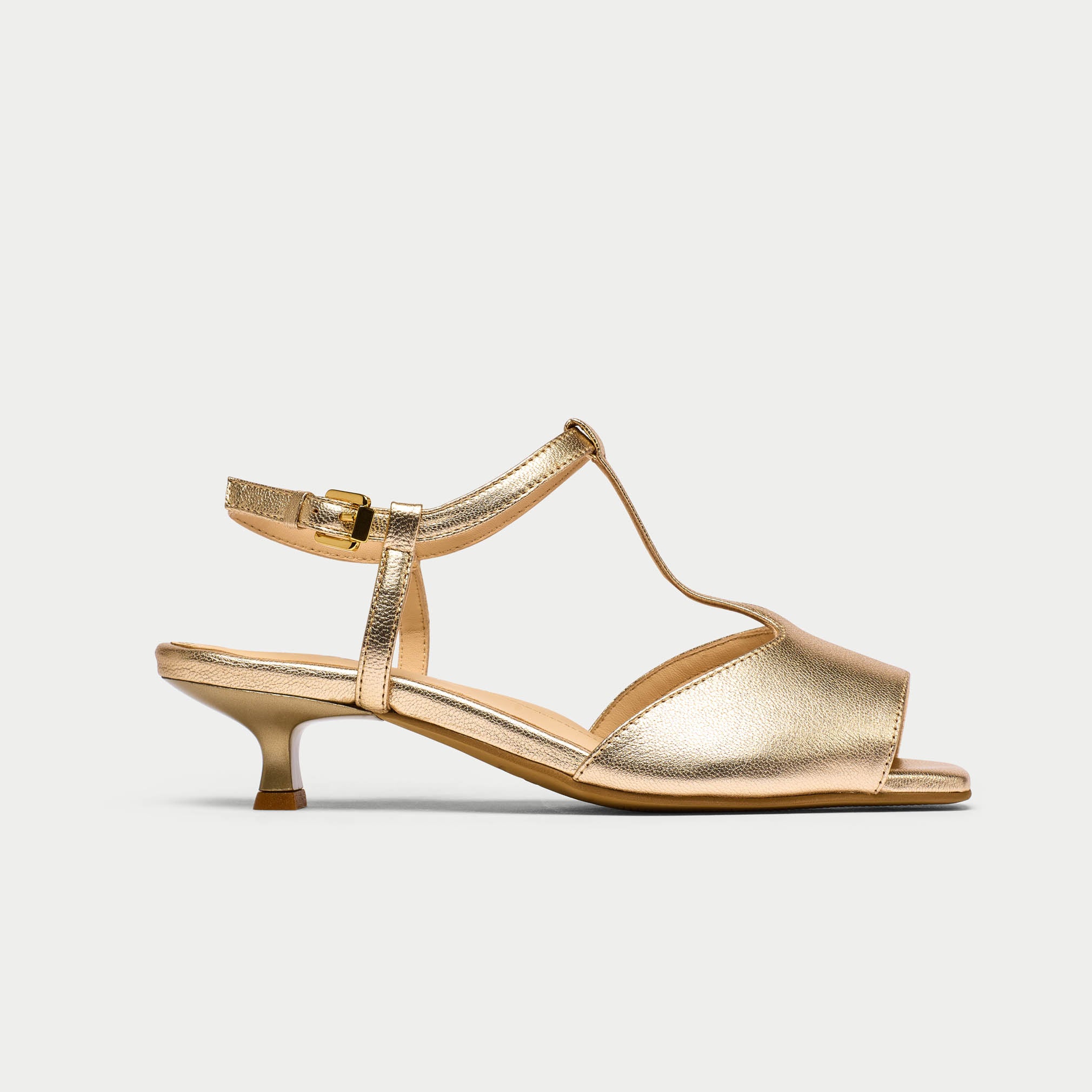 Gold sandal with a thin strap on a light gray background