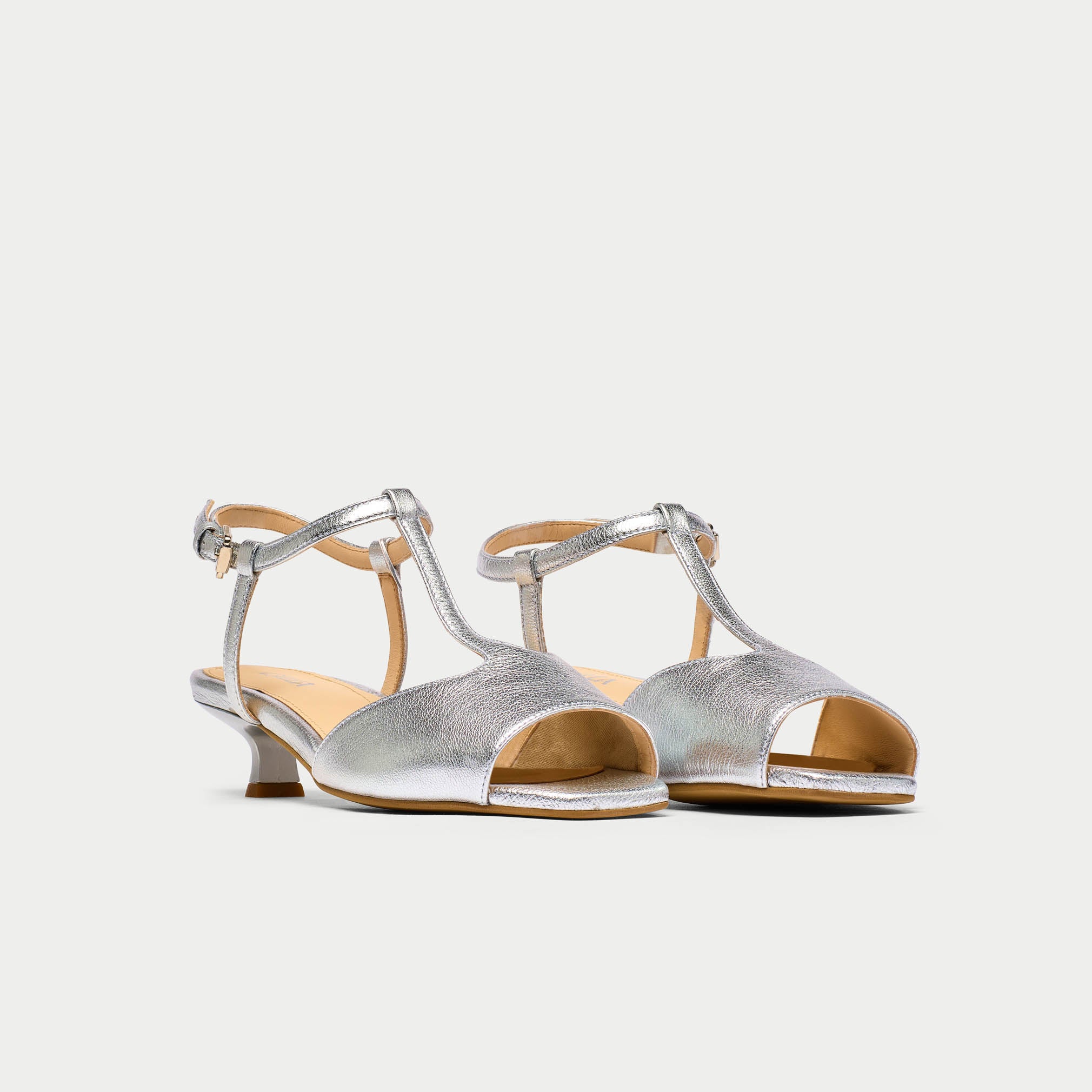Pair of silver open-toe shoes with thin straps on a white background