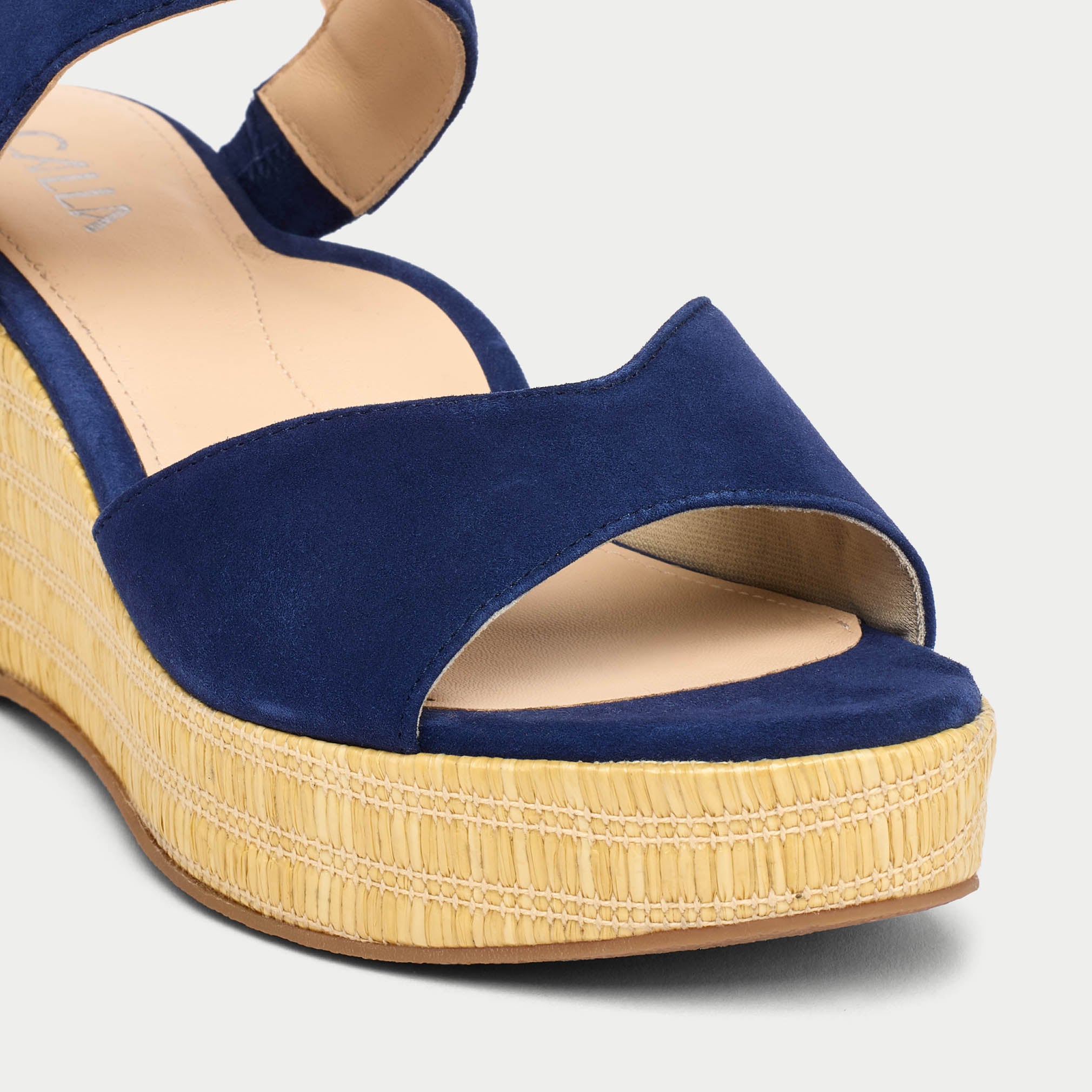 Blue wedge sandal with a textured beige sole on a light gray background