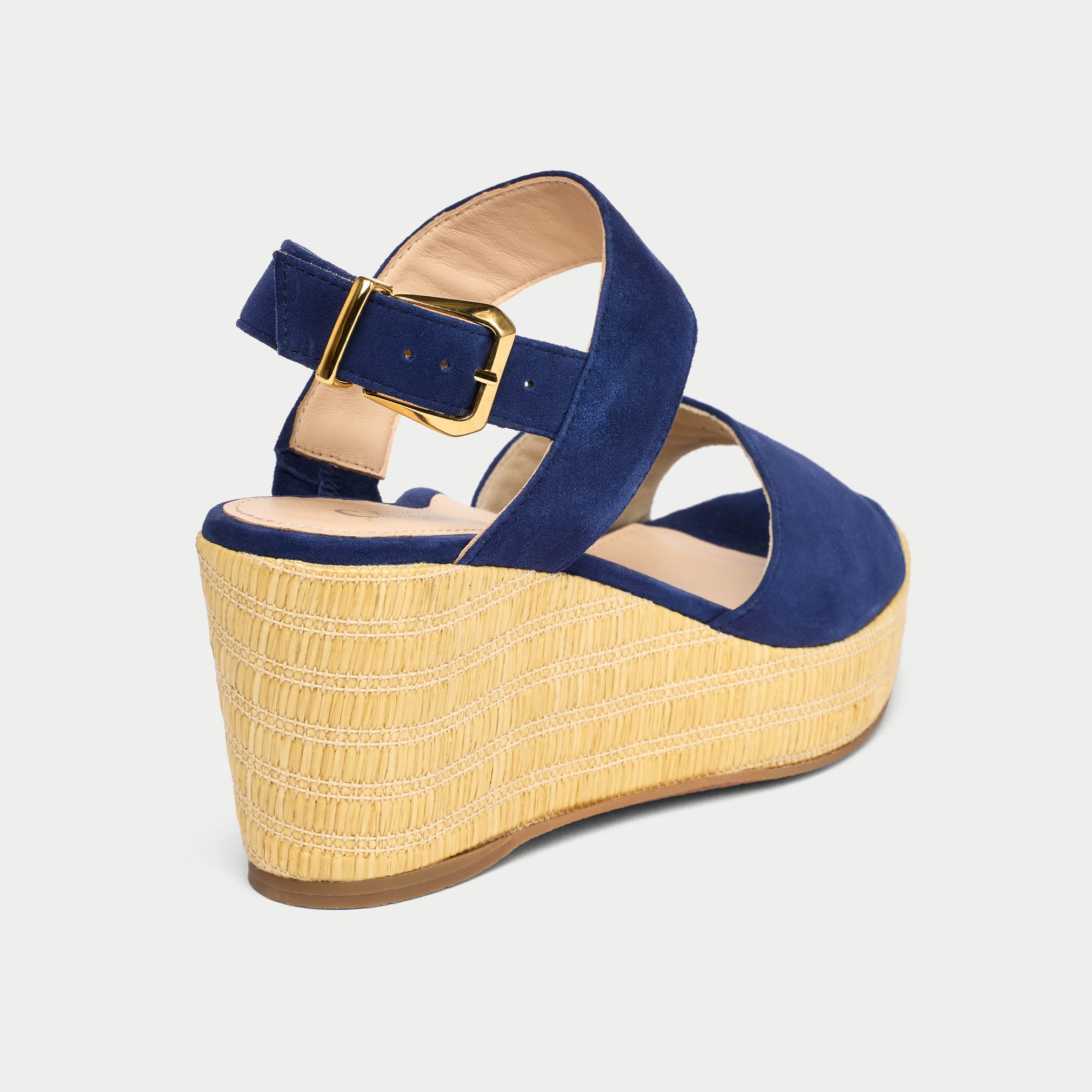 Blue wedge sandal with a gold buckle on a light gray background