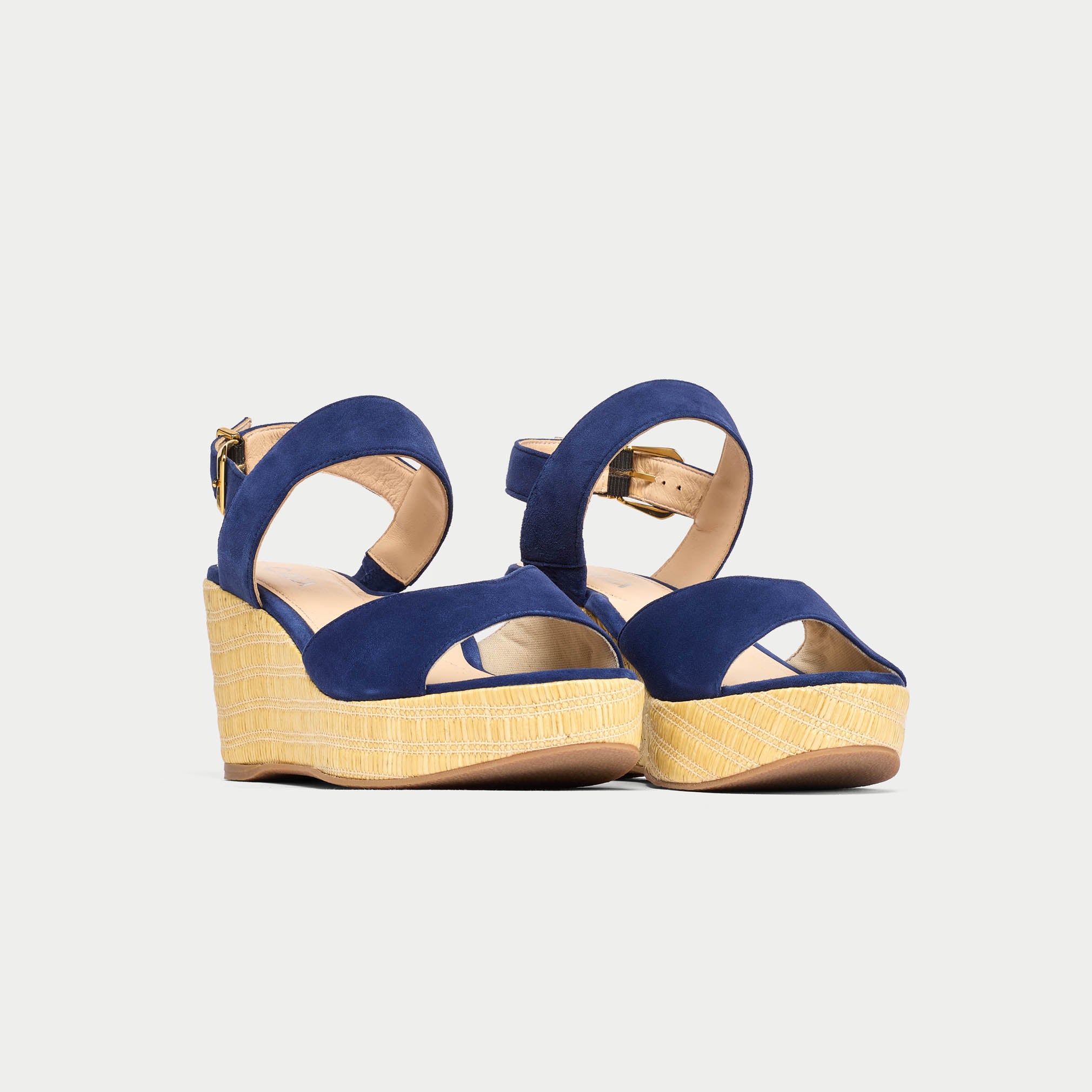 Navy wedge sandals with beige soles on a light gray background