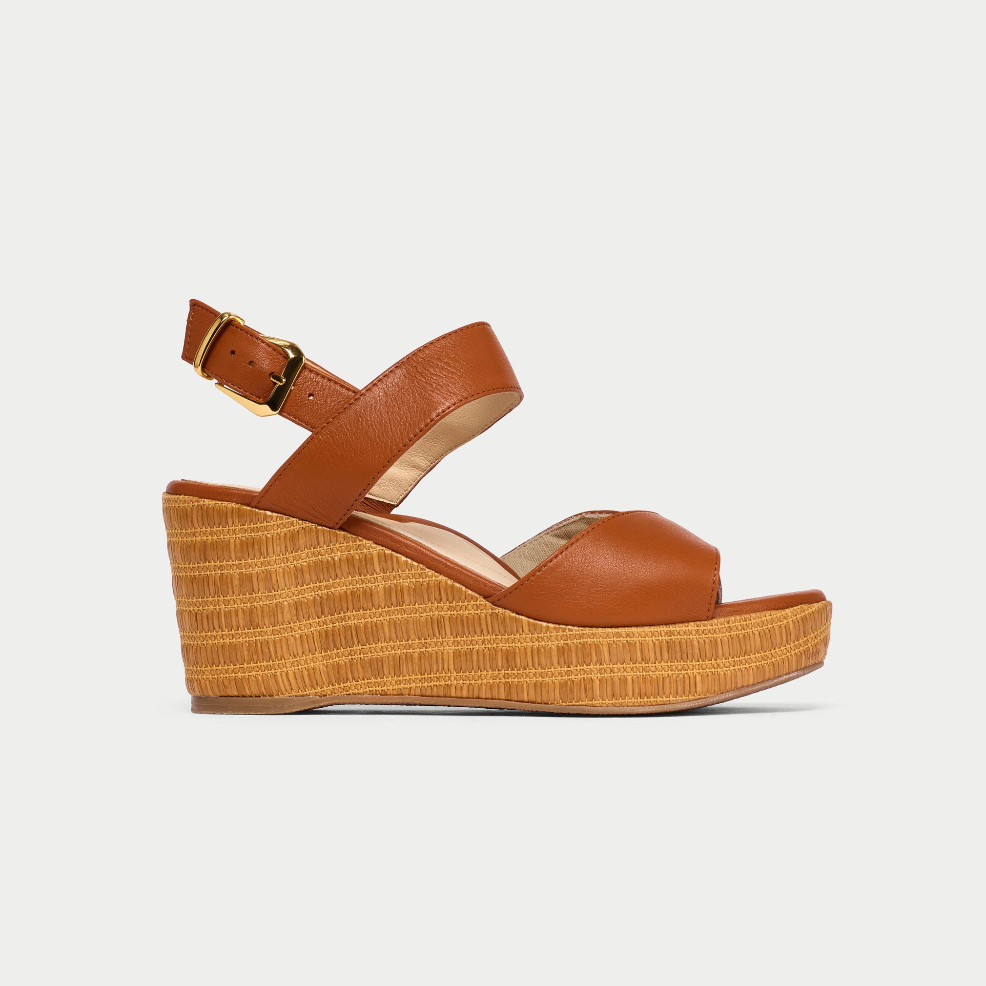Brown wedge sandal with raffia sole on a light gray background