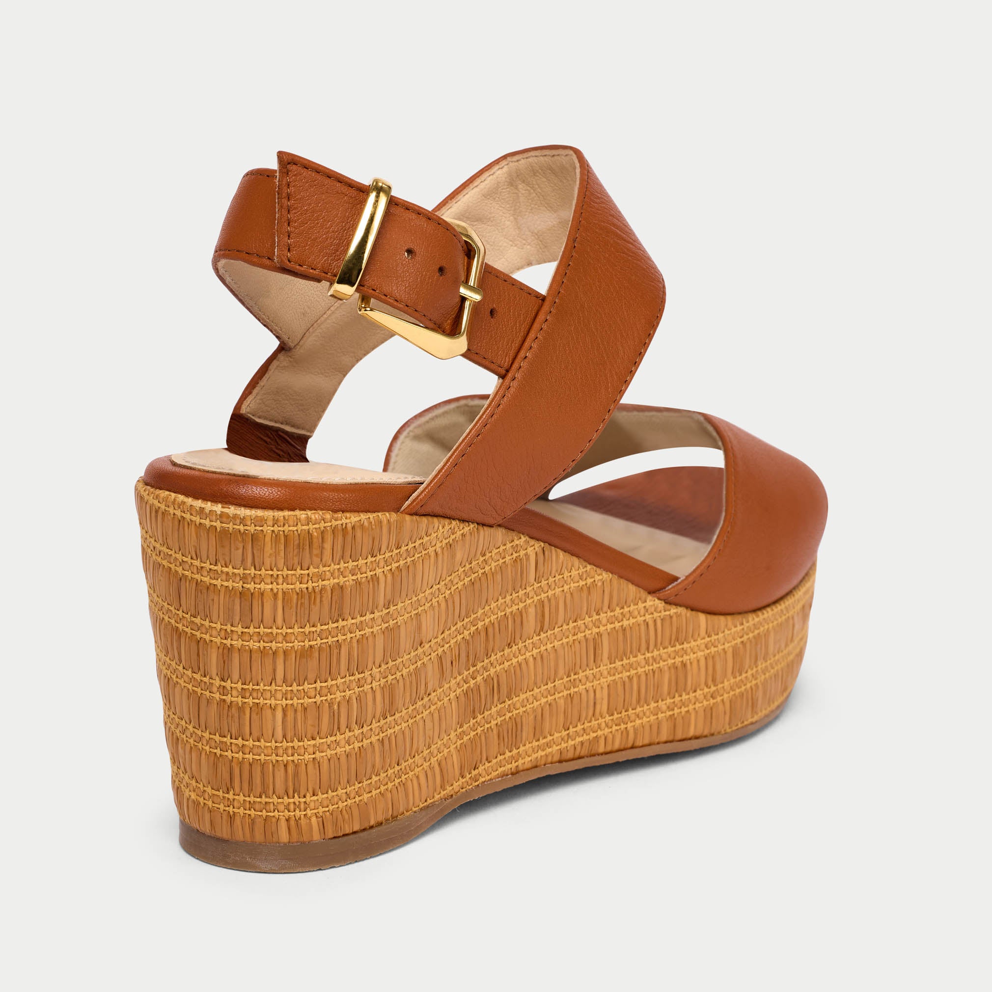 Brown wedge sandal with woven platform on a light gray background