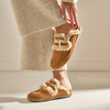 Brown slippers with fur trim worn by a person in a beige sweater.