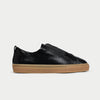 Black slip-on sneaker with brown sole on a light gray background