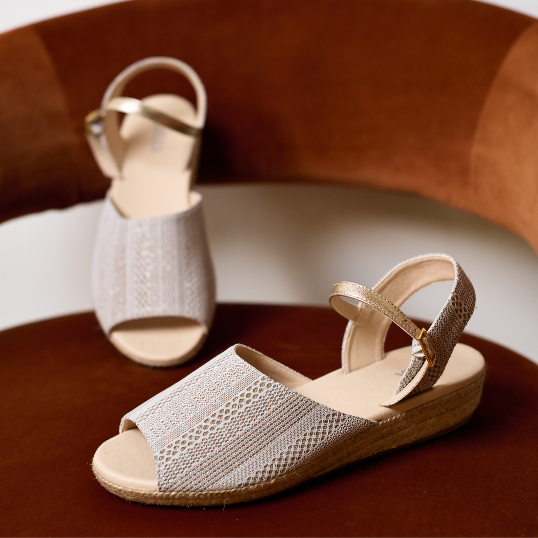 Pair of beige sandals on a brown surface with a blurred background