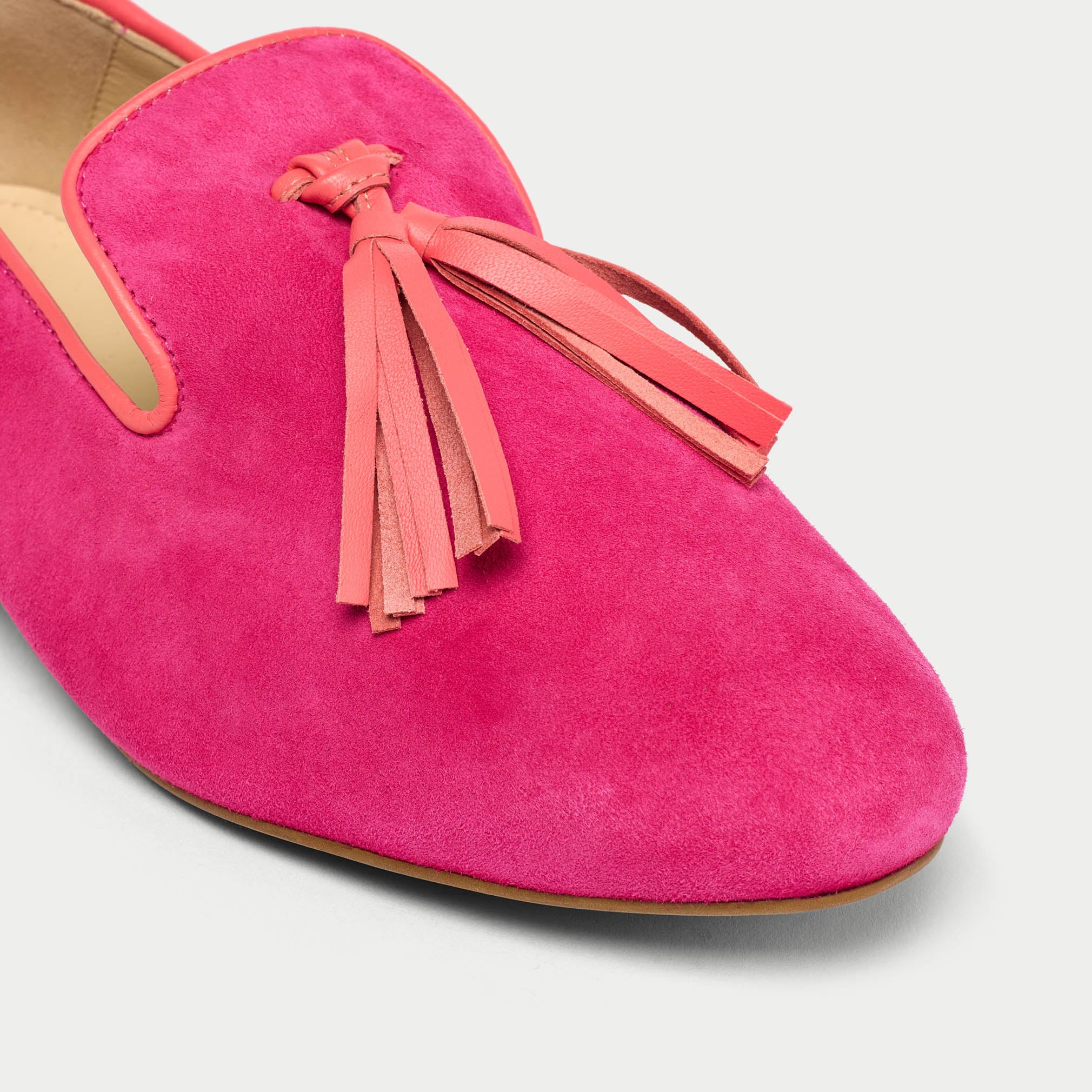Pink suede shoe with tassel on a light gray background