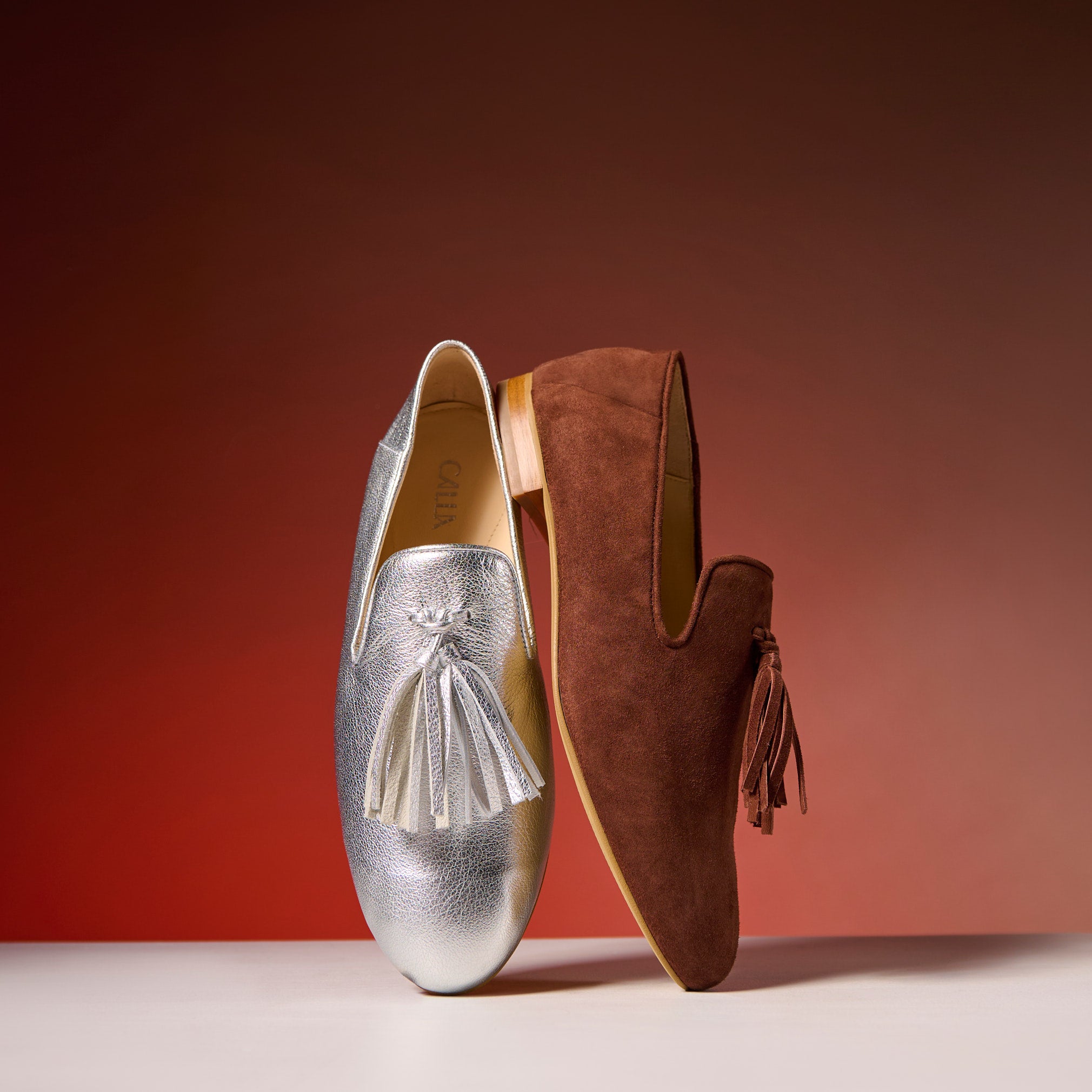 silver and brown loafers on a red background