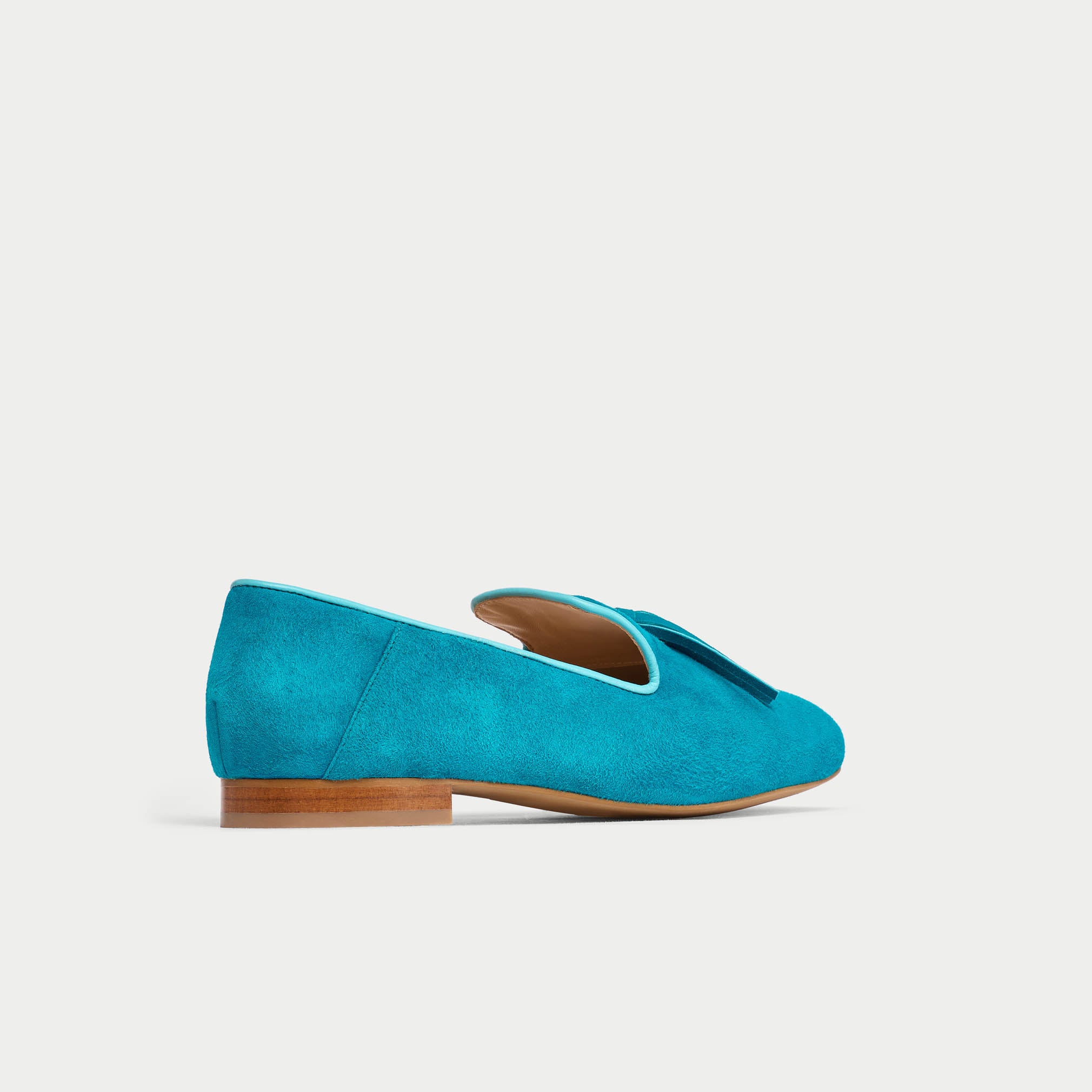 Blue suede loafer shoe on a light gray background