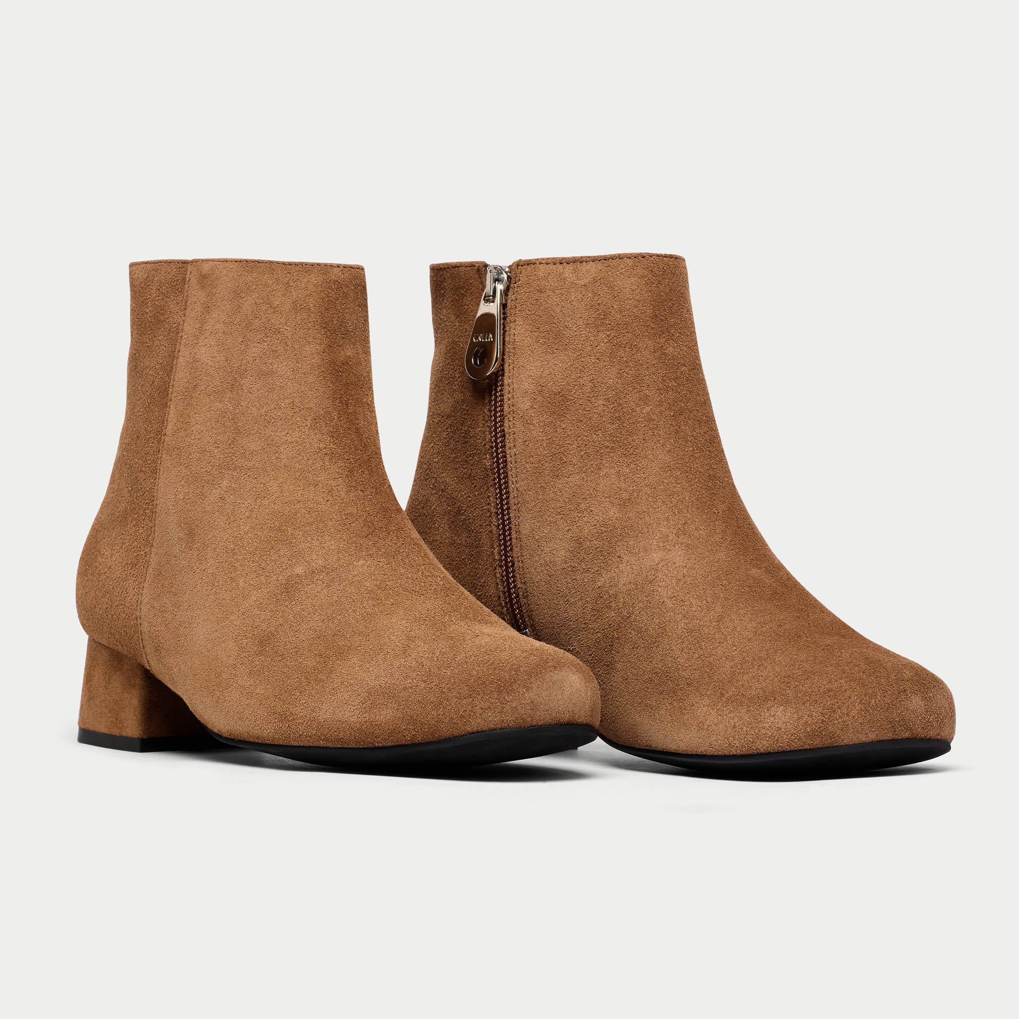 Pair of brown suede ankle boots on a light gray background