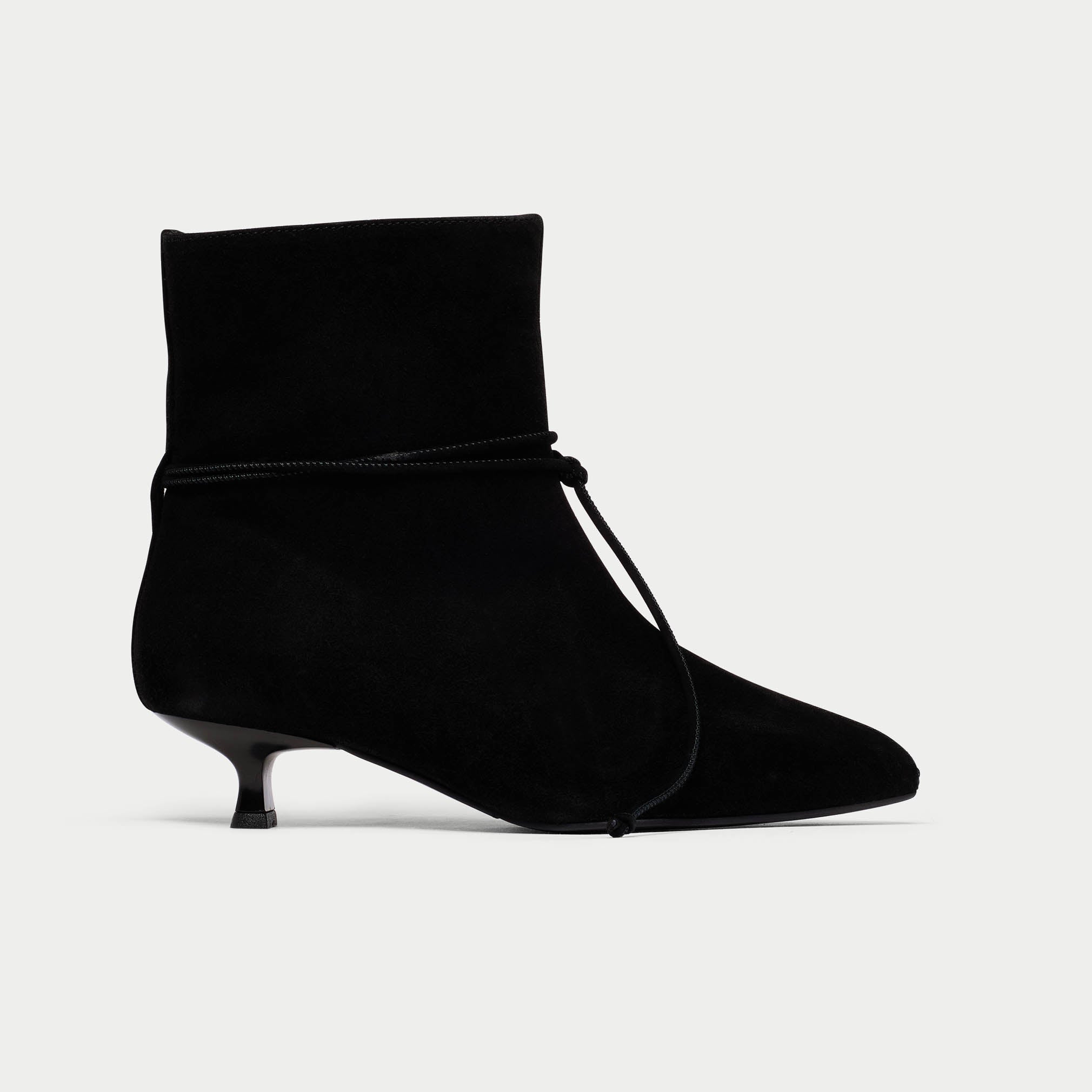 Black ankle boot with a kitten heel on a light gray background
