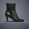 Maya Black ankle boot for bunions with a gold chain on a light gray background