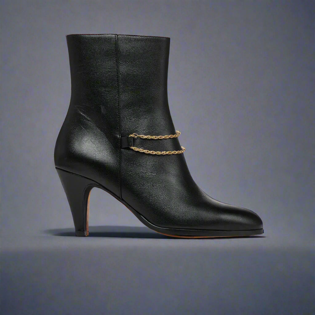 Maya Black ankle boot for bunions with a gold chain on a light gray background