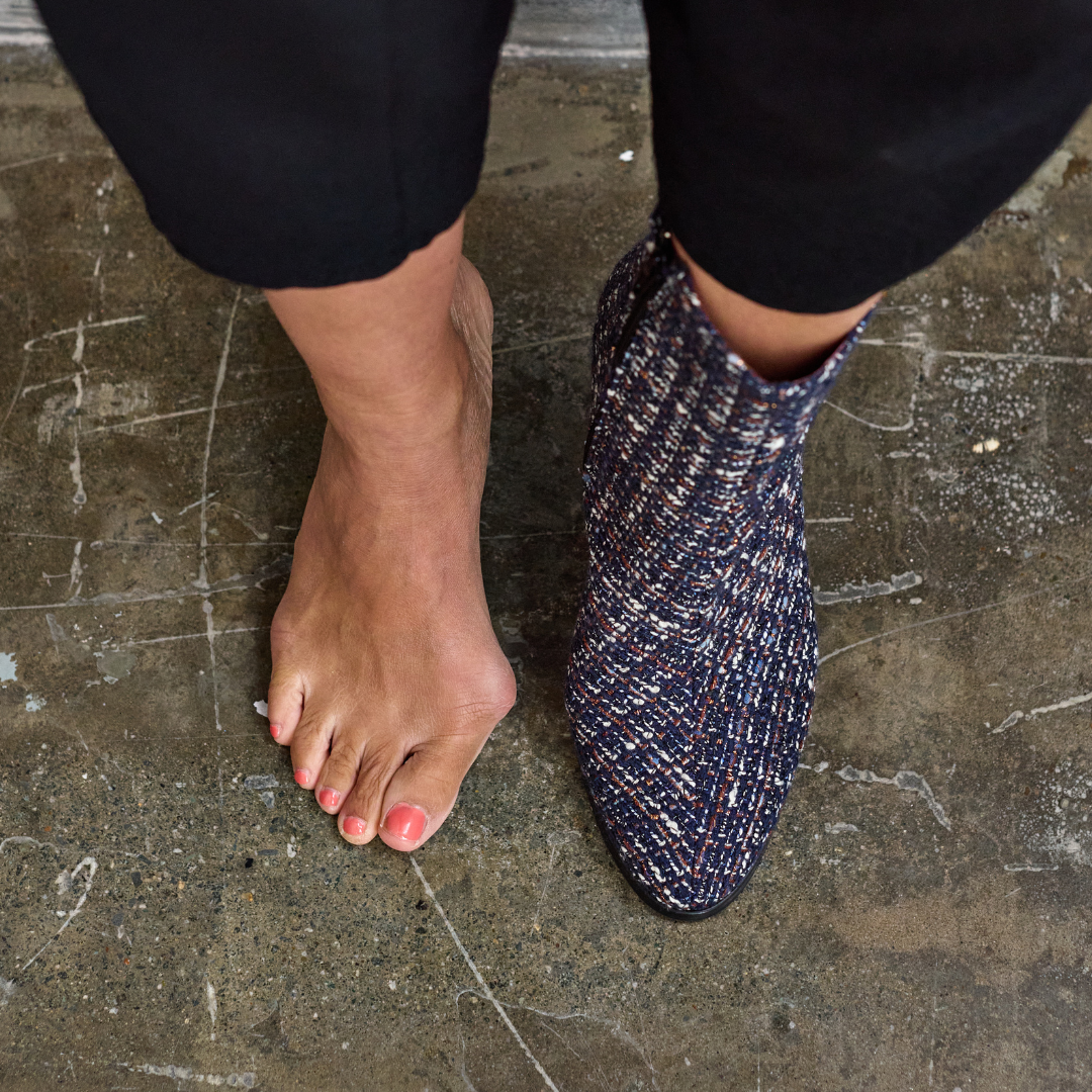 Person wearing Maya blue textured ankle boot on a concrete floor.