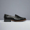Black Nadia crocodile-patterned loafers on a gray background