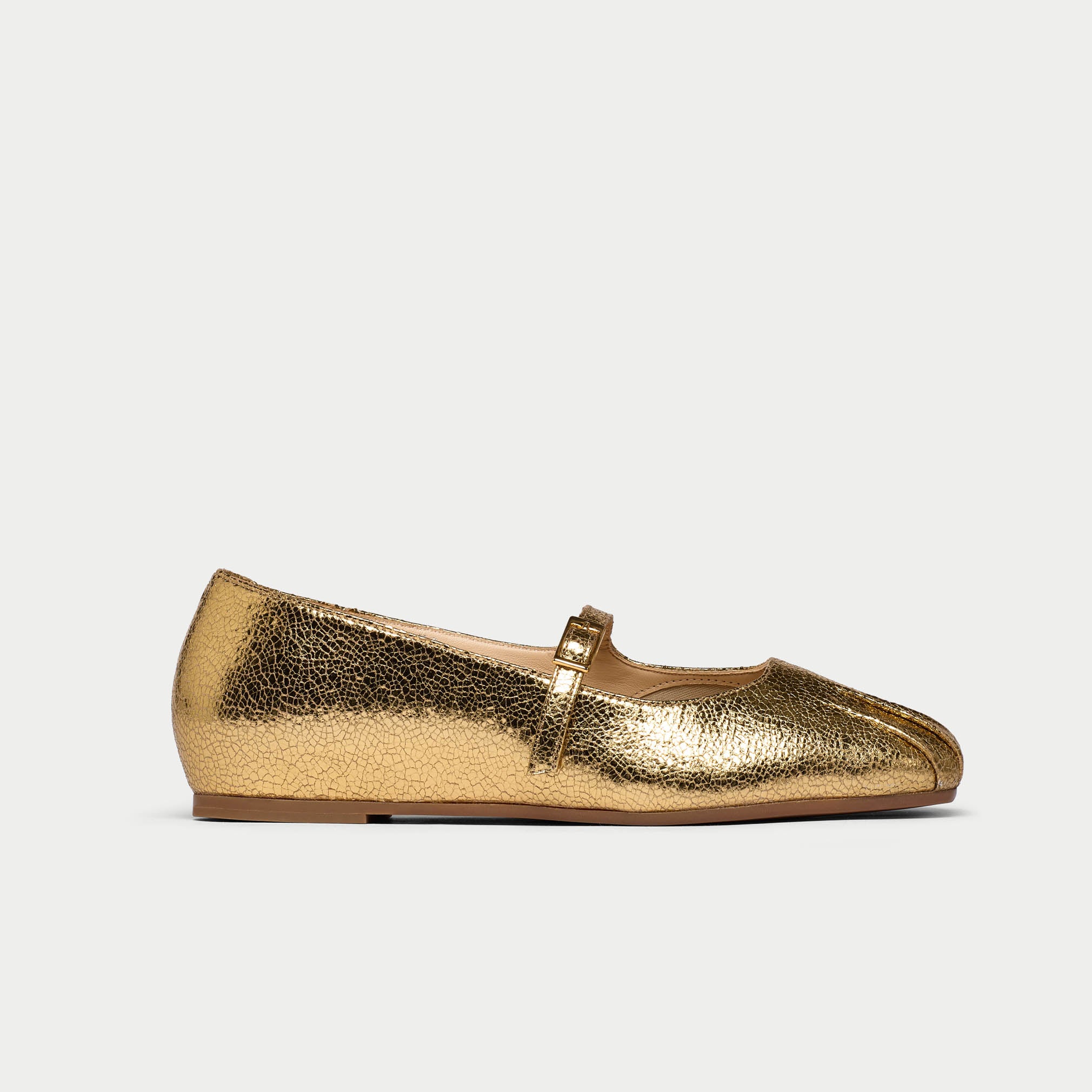 Gold metallic flat shoe on a light gray background