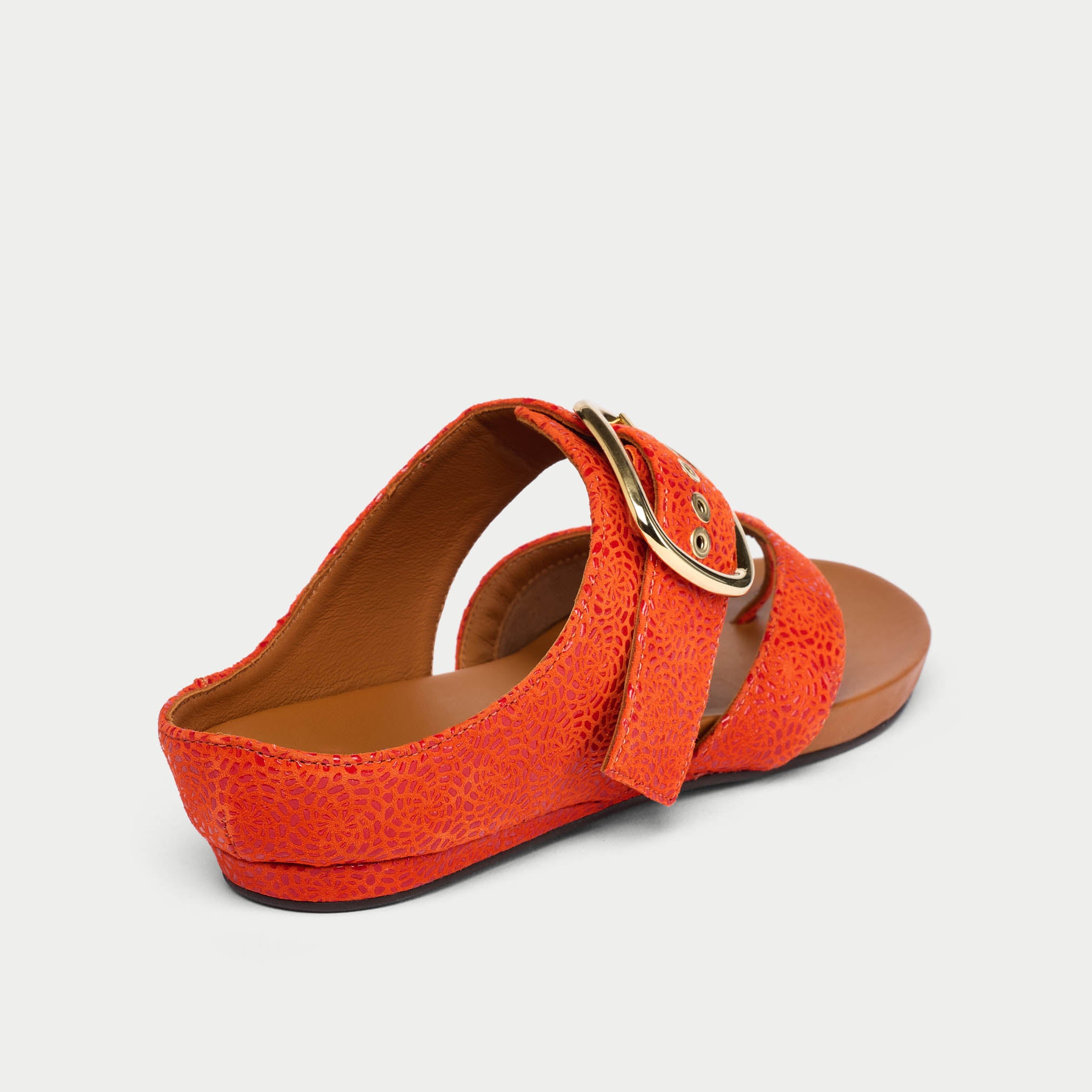 Orange sandal with a gold buckle on a light gray background