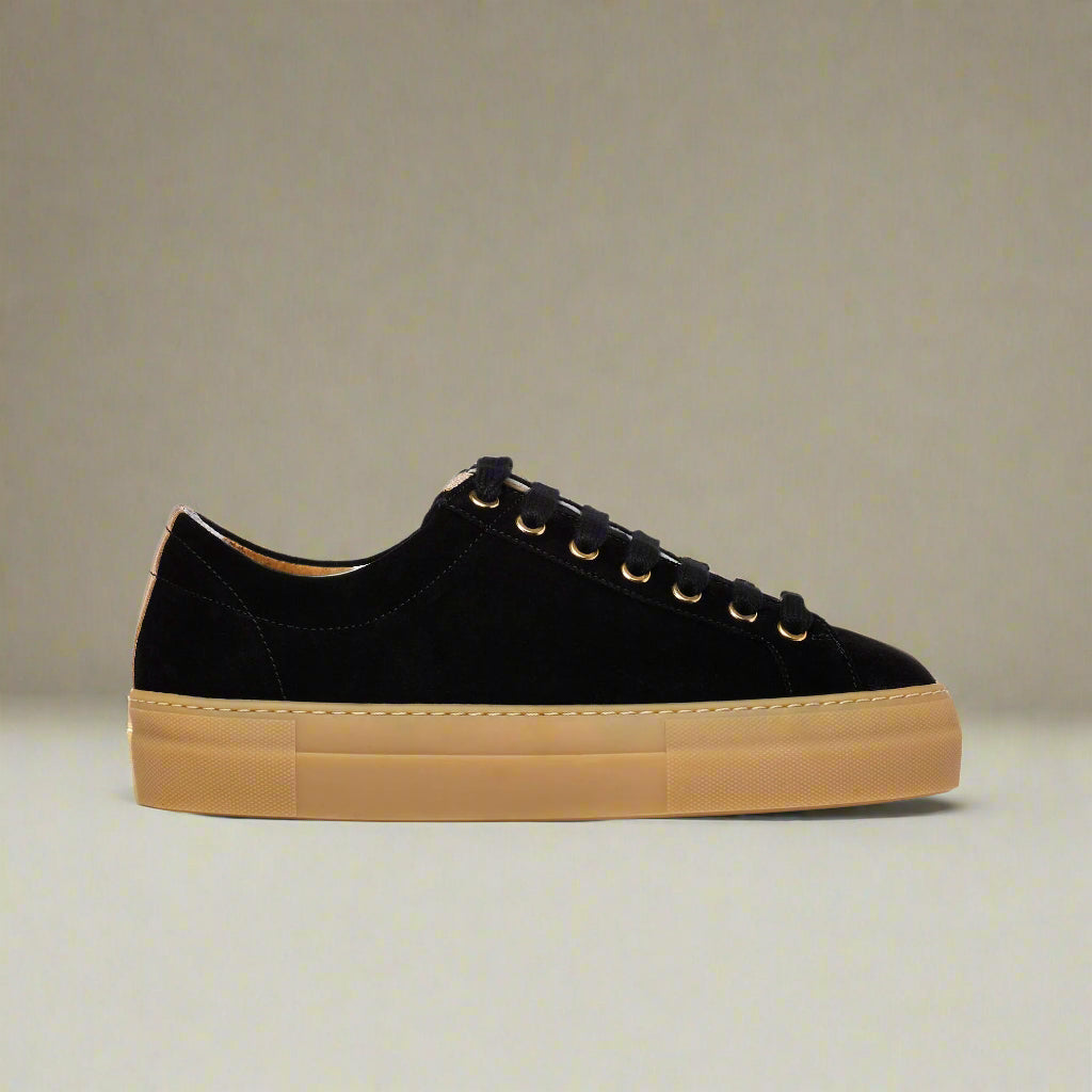 Black Saturn sneaker with tan sole on a light beige background
