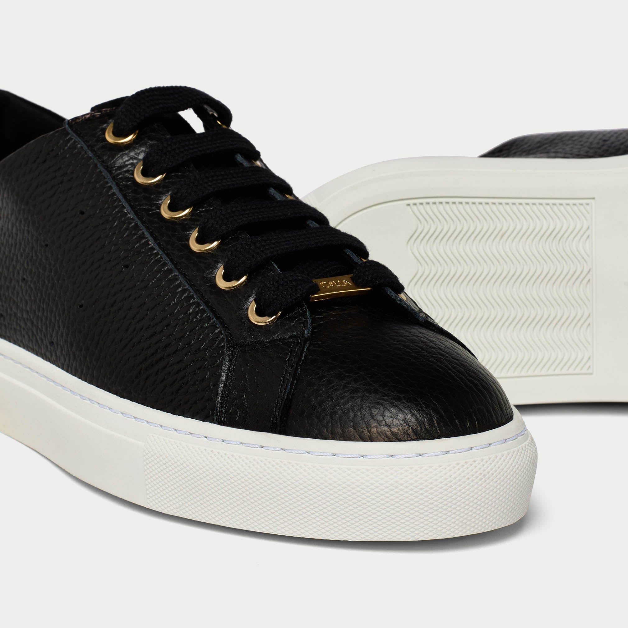 Black leather sneaker with white sole on a light gray background