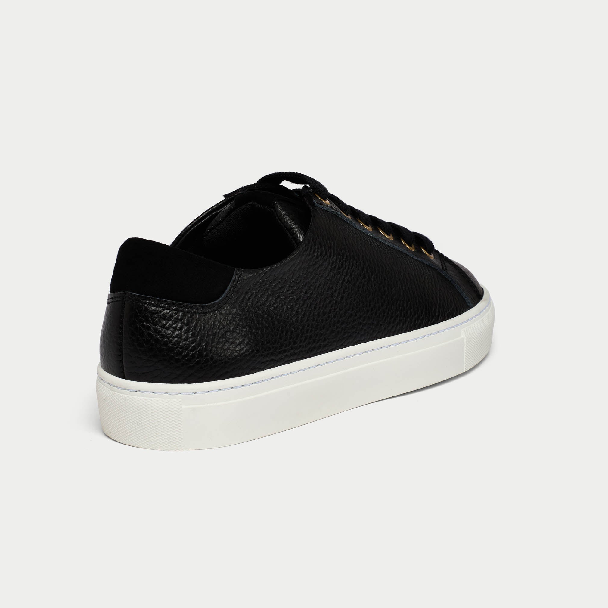 Black leather sneaker with white sole on a light gray background